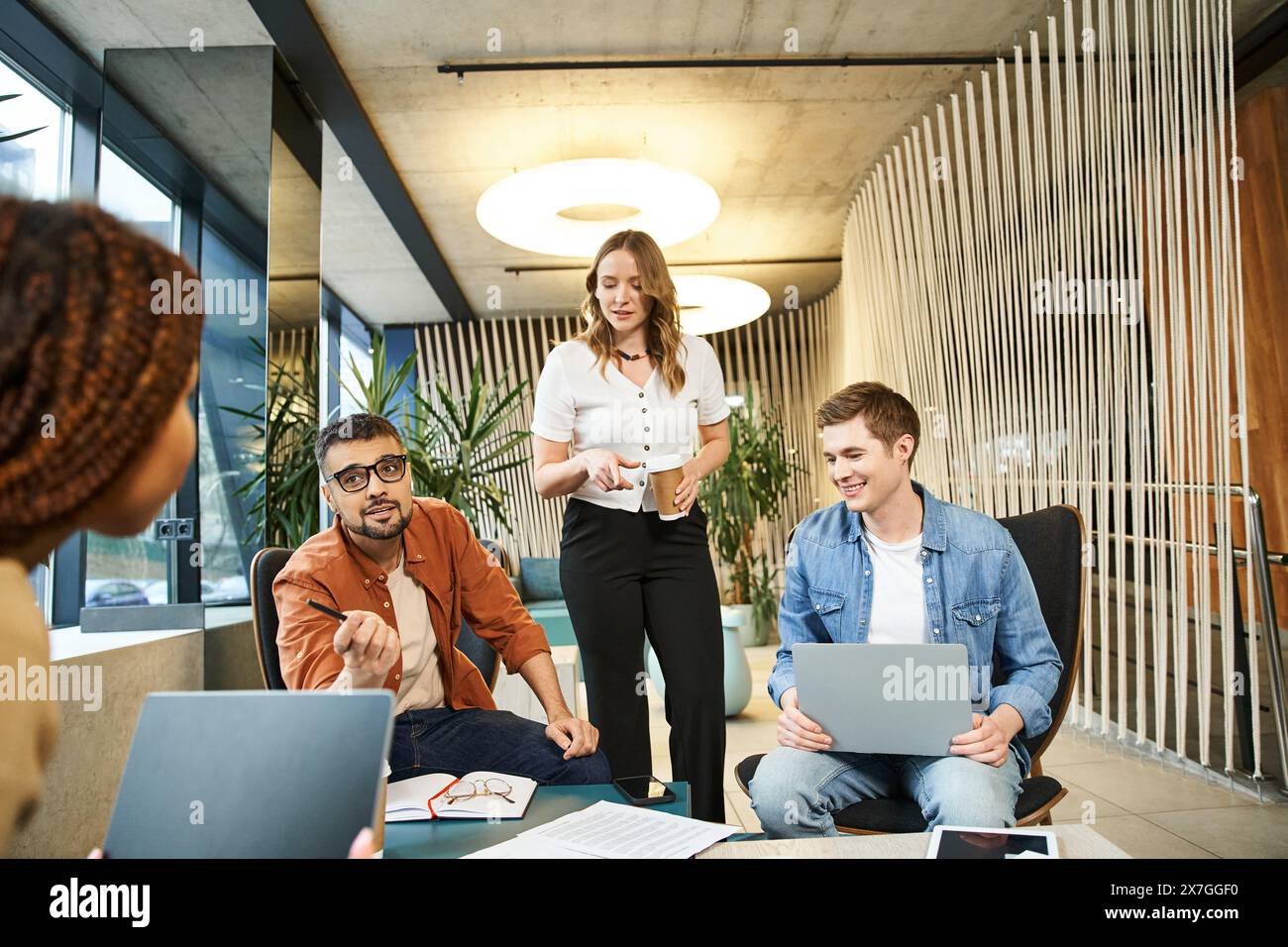 Un team di colleghi e professionisti delle startup si è riunito intorno a un tavolo, ognuno dei quali si è concentrato sui propri notebook, collaborando a un progetto. Foto Stock
