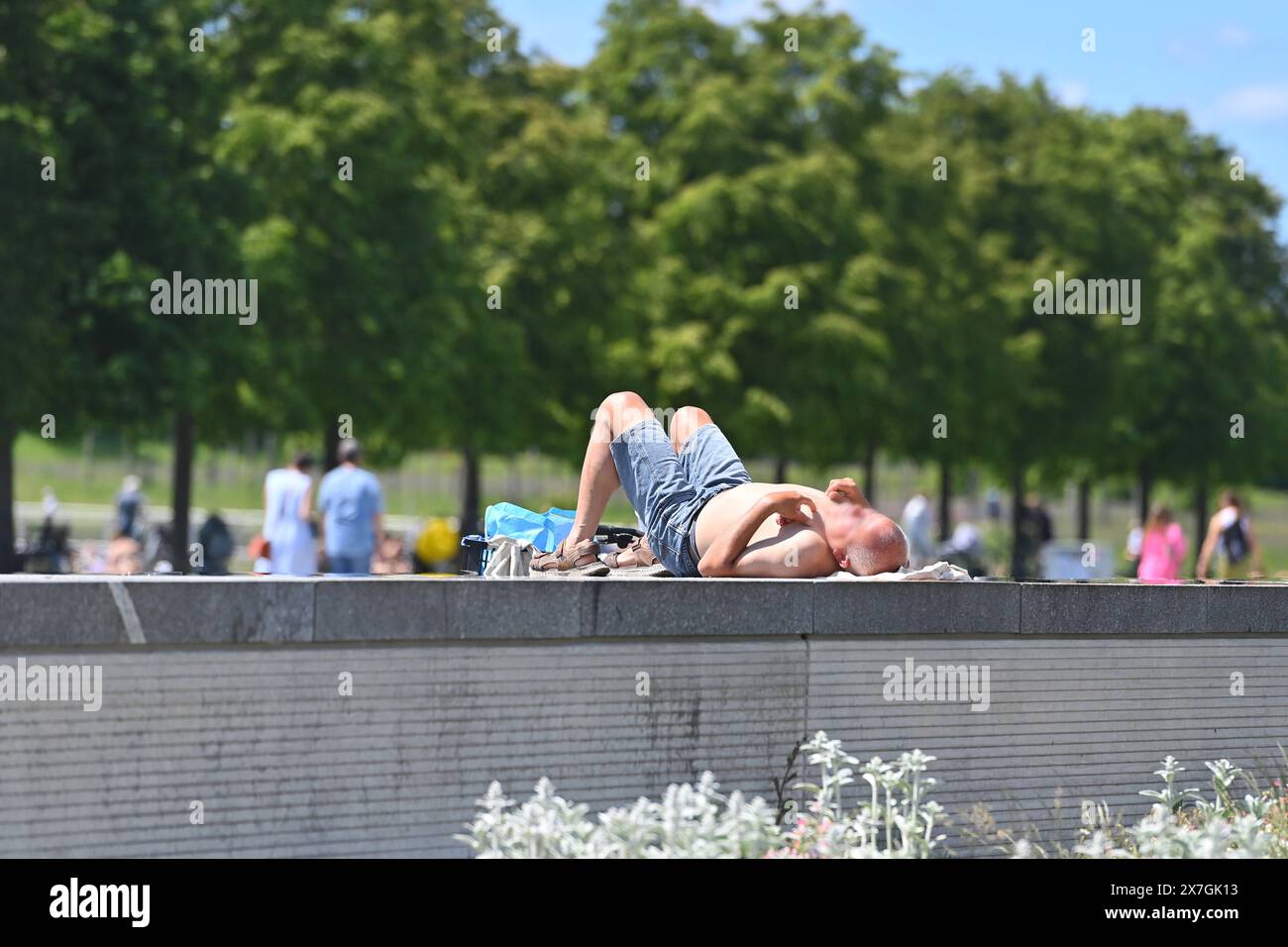 Aelterer Mann sonnt sich im Riemer Park a Monaco. Er liegt auf einer Steinmauer mit freiem Oberkoerper und tubo flessibile kurzer. *** Uomo anziano che prende il sole nel Parco Riemer di Monaco è sdraiato su un muro di pietra con la parte superiore del corpo esposto e indossa pantaloncini corti Foto Stock