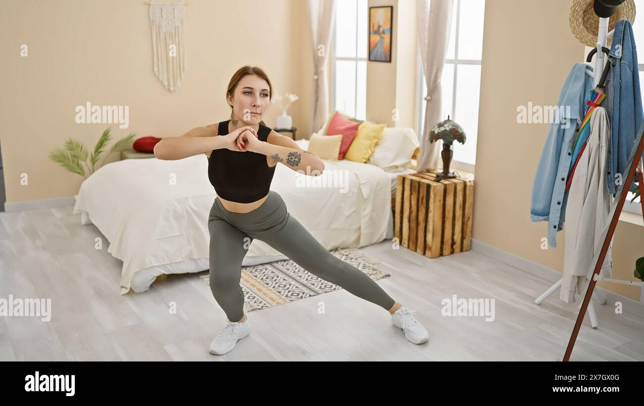 Una giovane donna caucasica si esercita in una spaziosa camera da letto, indossando abbigliamento sportivo e mostrando sicurezza. Foto Stock Una giovane donna caucasica si esercita in una spaziosa camera da letto, indossando abbigliamento sportivo e mostrando sicurezza. Foto Stock