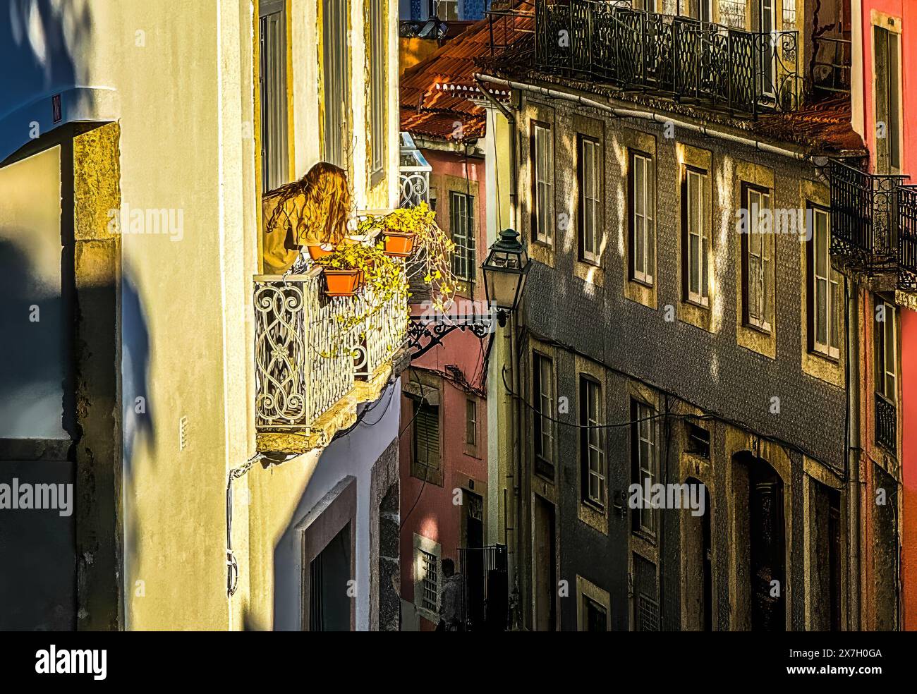 Lisbona, quartiere Bica vicino a Bairro alto. Una bella giovane donna guarda fuori da una finestra di un edificio storico. Foto Stock