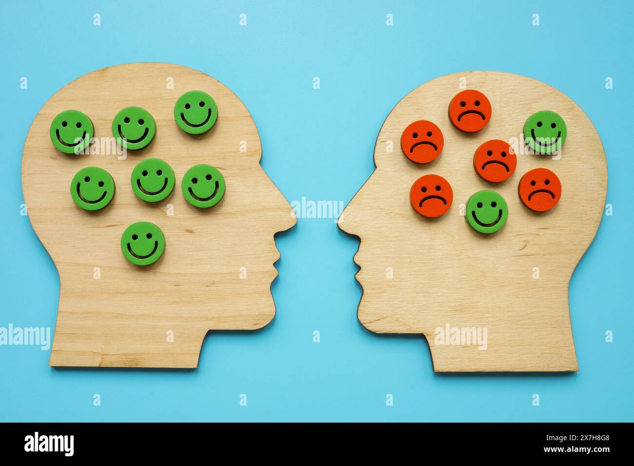 Contorni in legno di teste, sorrisi felici e tristi. Stress, emozioni negative e concetto di psicoterapia. Foto Stock