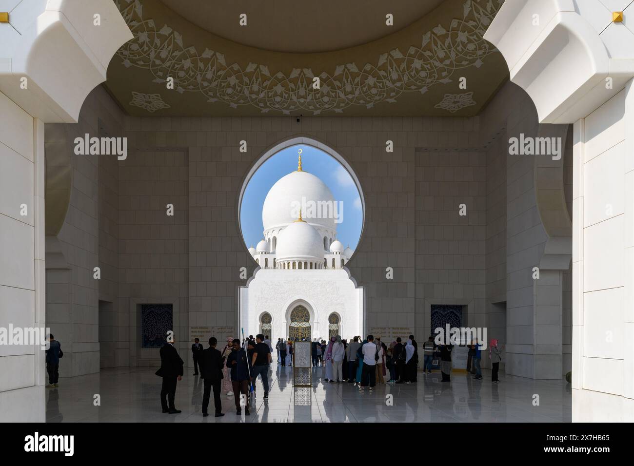 Abu Dhabi, Emirati Arabi Uniti - 4 gennaio 2024: I visitatori si riuniscono all'ingresso della grande Moschea dello sceicco Zayed, che mostra le sue splendide cupole bianche e le sue intricate Foto Stock