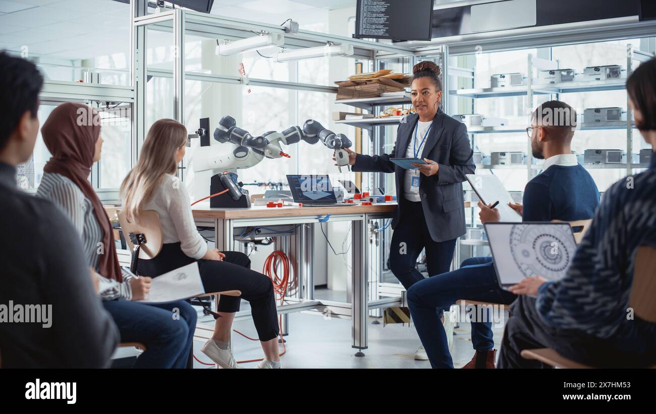 Black Professional Engineer parla con gli sviluppatori futuri e spiega come costruire in modo efficiente macchine che replicano le azioni umane, utilizza il tablet per illustrare metodi e soluzioni di lavoro. Foto Stock