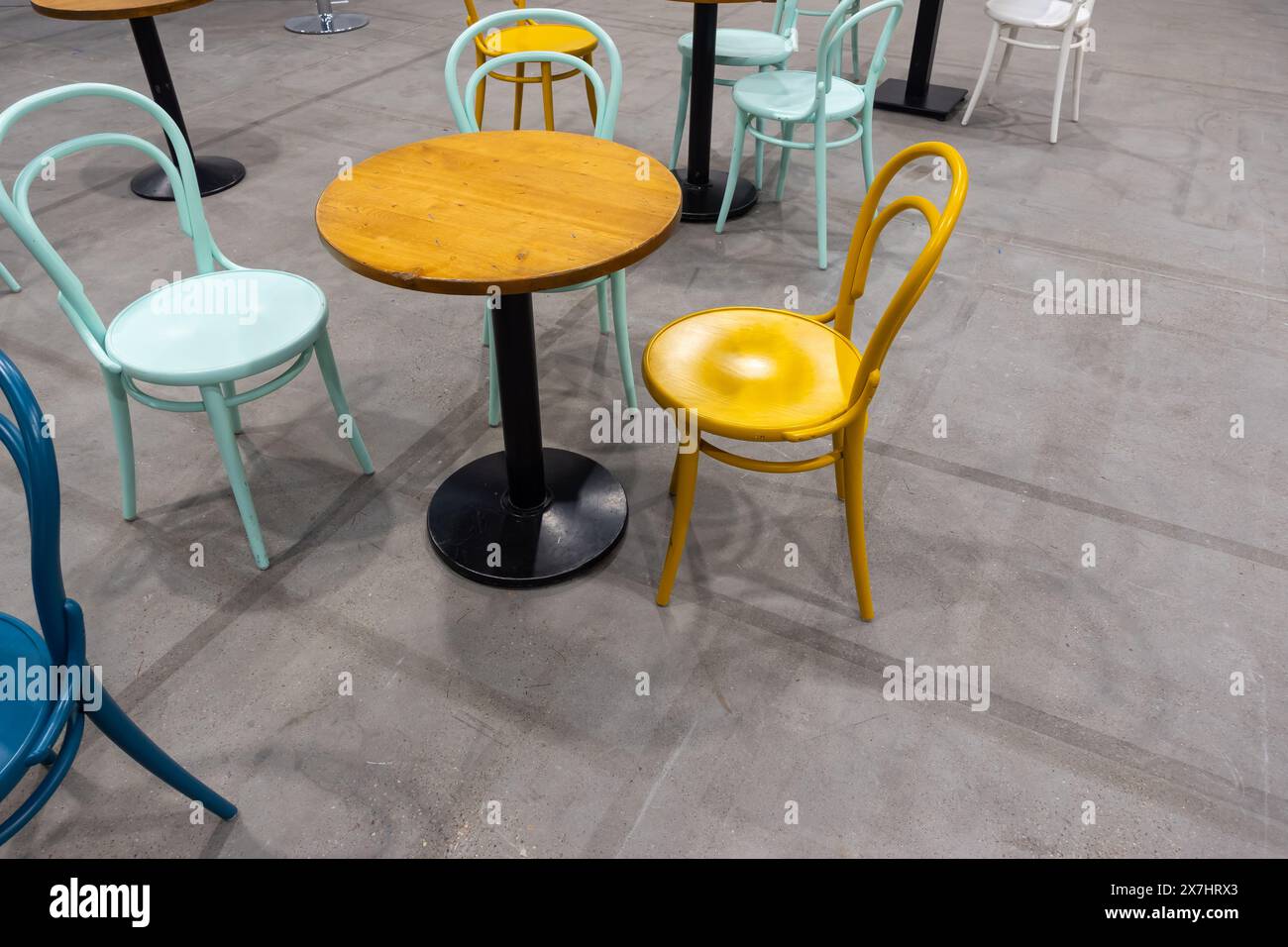 Sedie e tavoli di legno colorati in un ristorante pubblico. Posti pubblici per mangiare pasti veloci. Foto Stock