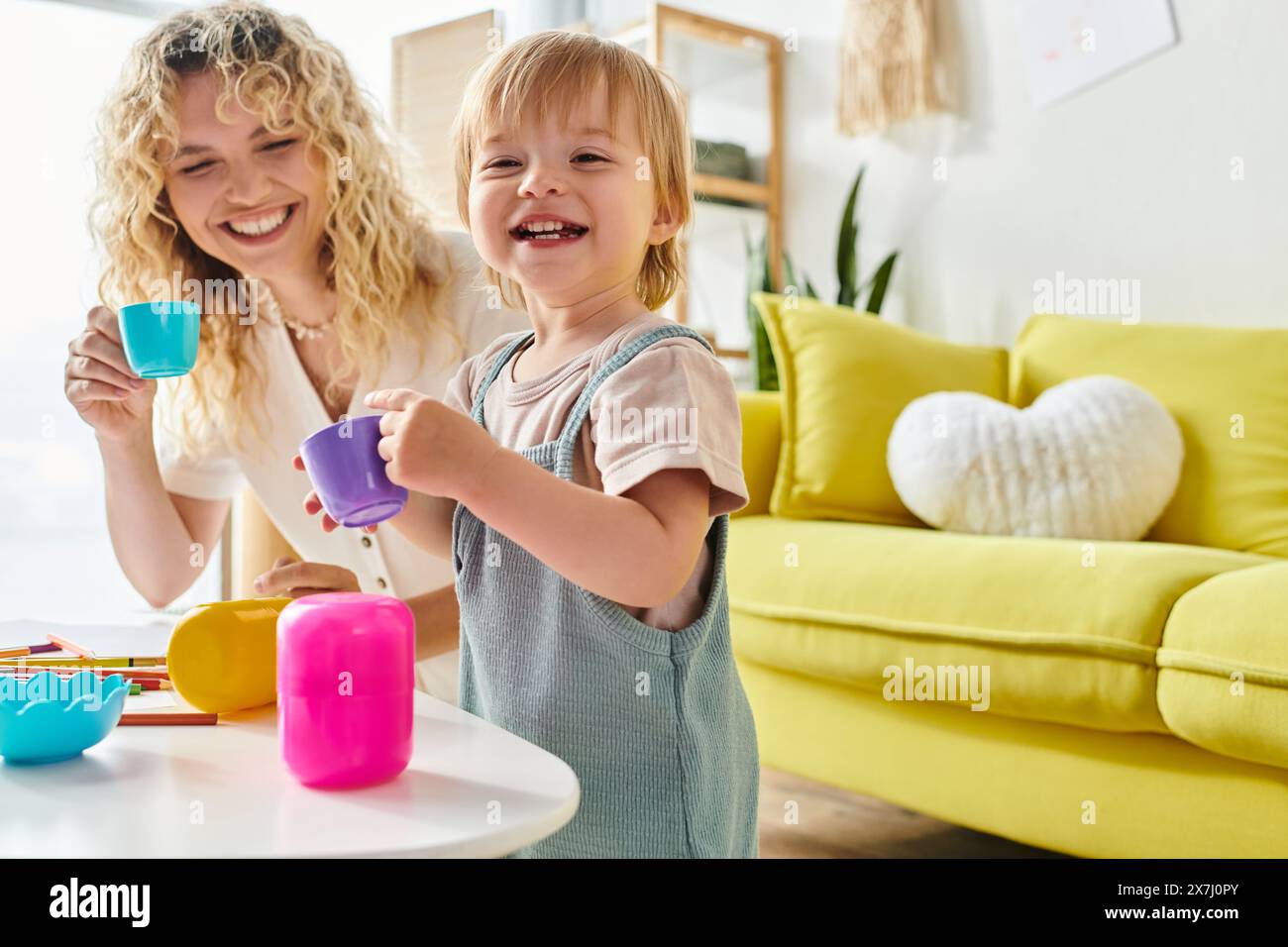 La madre riccia e la figlia del bambino esplorano giocosamente le attività della coppa Montessori a casa. Foto Stock