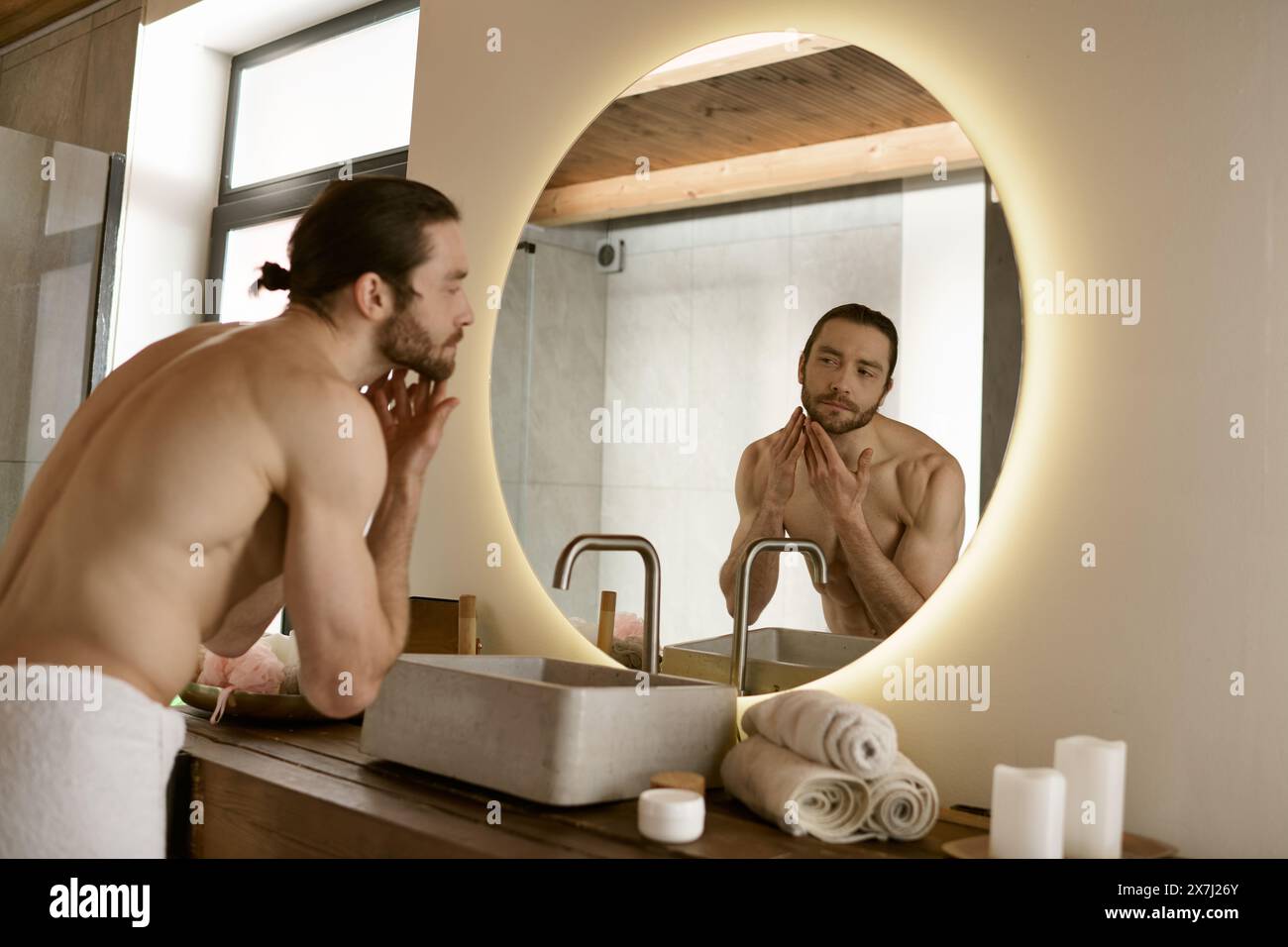 Bell'uomo che cura il corpo davanti allo specchio del bagno a casa. Foto Stock