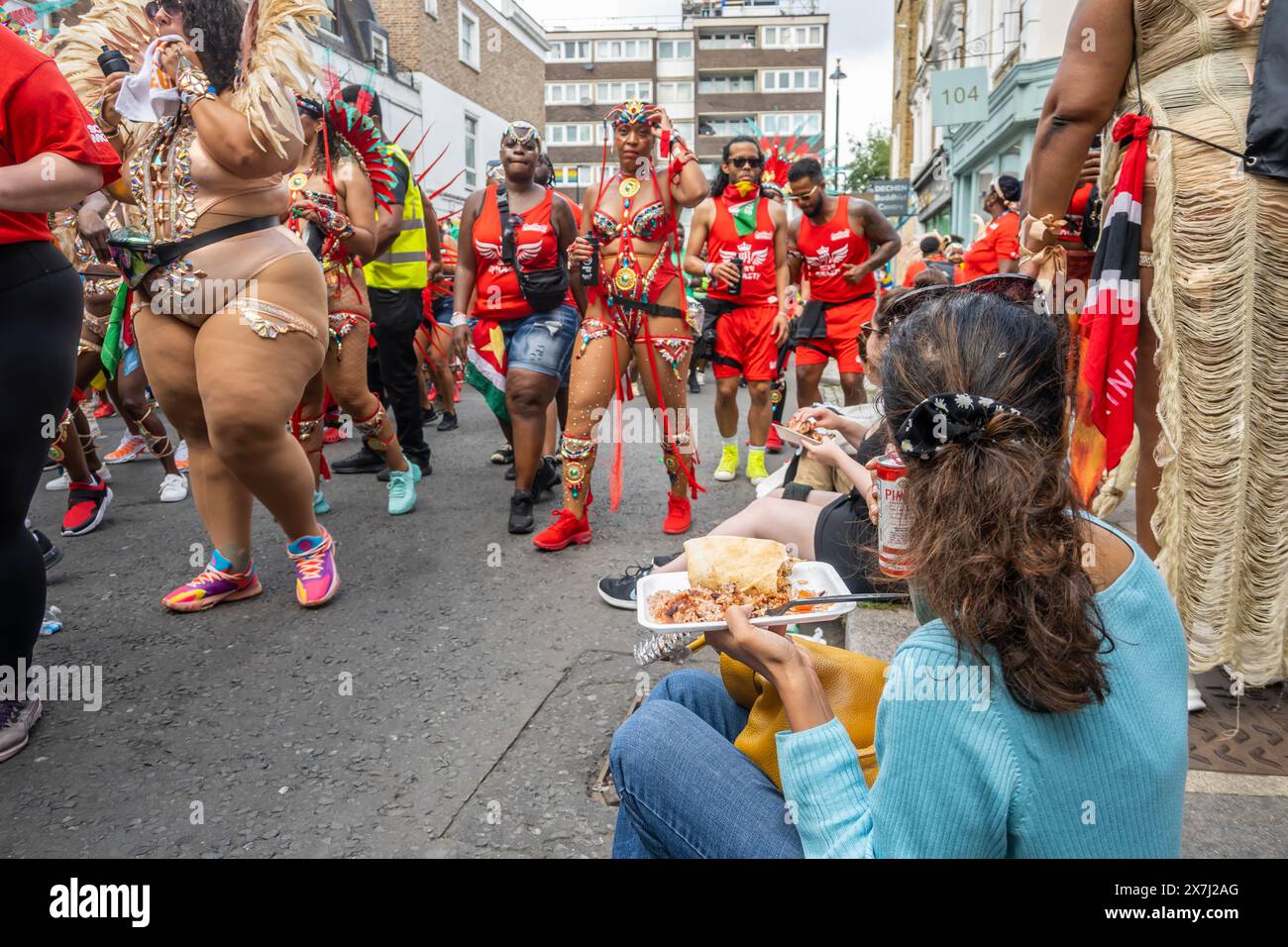 NOTTING HILL, LONDRA, INGHILTERRA - 28 agosto 2023: La gente sedeva a mangiare cibo di strada su un marciapiede al Carnevale di Notting Hill nel 2023 Foto Stock
