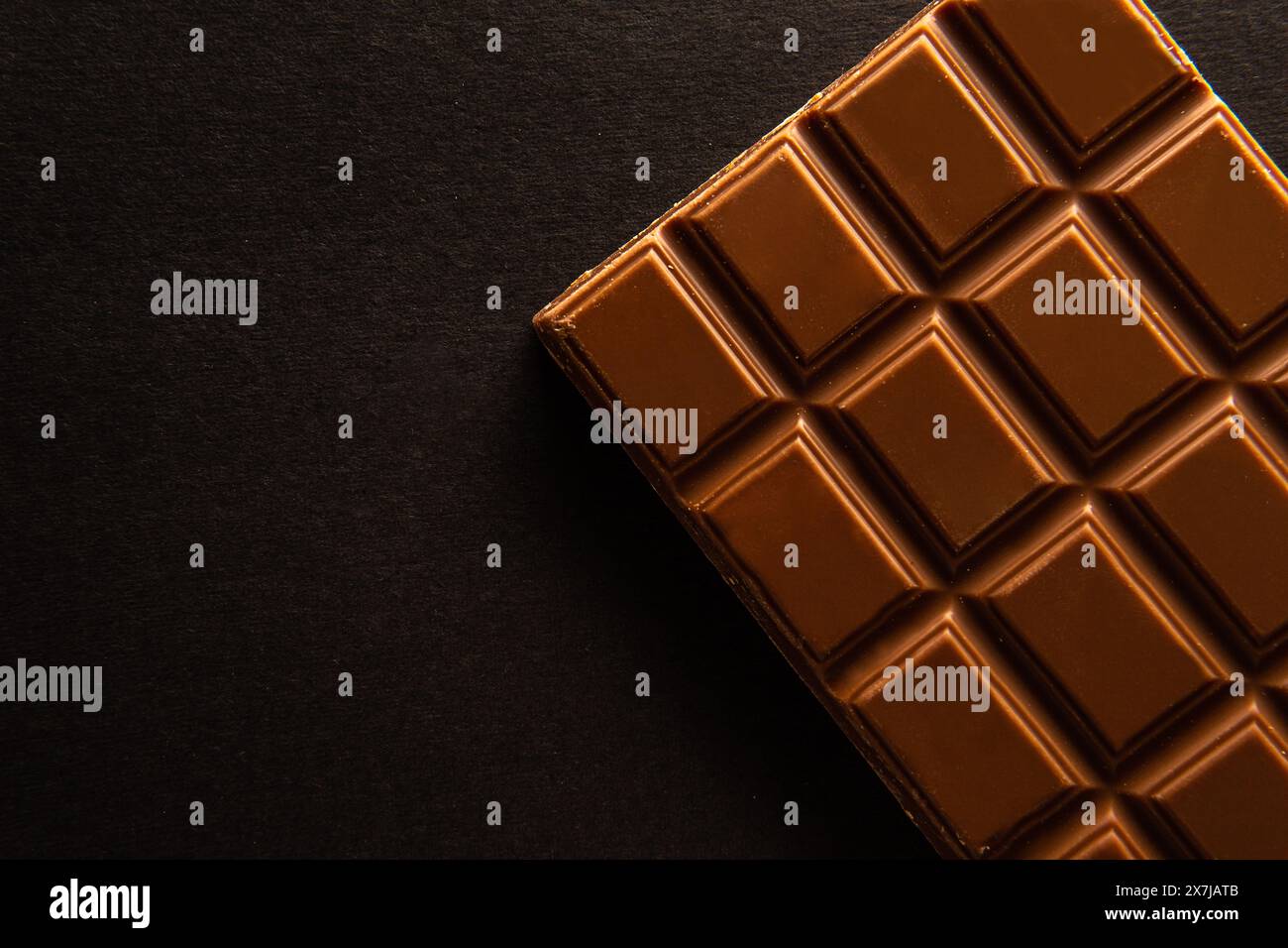 Foto sopra la testa di un pezzo di cioccolato rettangolare su sfondo nero con spazio di copia Foto Stock