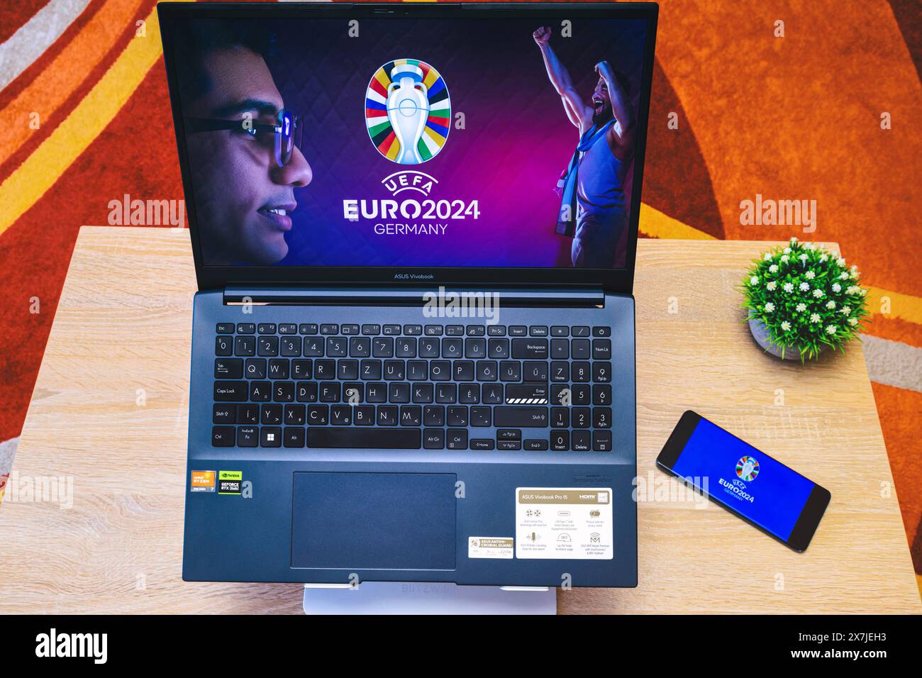 Sfondo del Campionato europeo di calcio UEFA 2024 sullo schermo di un laptop e logo del Campionato europeo di calcio UEFA 2024 sullo schermo del telefono, vista dall'alto Foto Stock
