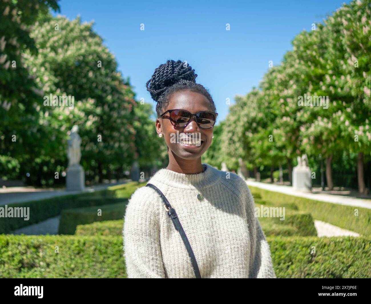 una giovane donna sorridente con gli occhiali da sole in un parco Foto Stock