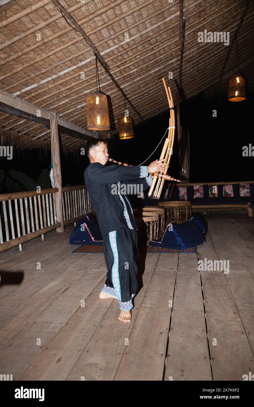 Un uomo hmong suona uno strumento musicale a Chiang Khong, nella provincia di Chiang Rai, nel nord della Thailandia, in colorato costume locale tradizionale Foto Stock