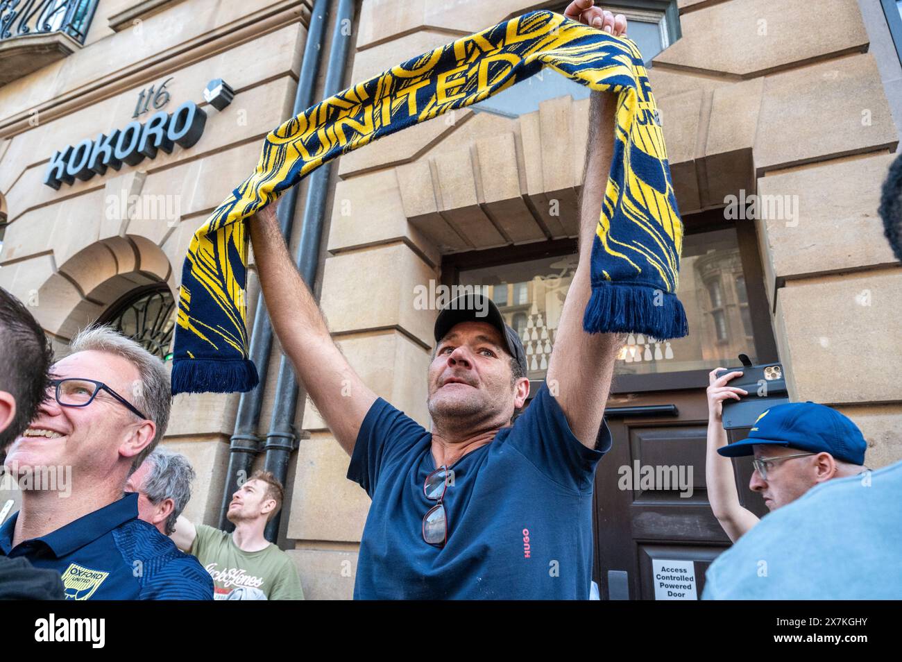 Migliaia di tifosi dell'Oxford United si sono schierati nel centro della città per celebrare la promozione dell'Oxford United al campionato EFL dopo aver battuto i Bolton Wanders nei playoff di League One a Wembley nel fine settimana. La folla, addobbata di giallo, applaudì forte e lasciava sfogarsi gialli mentre l'autobus scoperto che trasportava il team e il personale si muoveva lentamente lungo High Street fino al municipio di Oxford, dove partecipavano a un ricevimento civico solo su invito. La bandiera dell'Oxford United volò sopra l'edificio del Consiglio cittadino di Oxford per festeggiare. Foto Stock