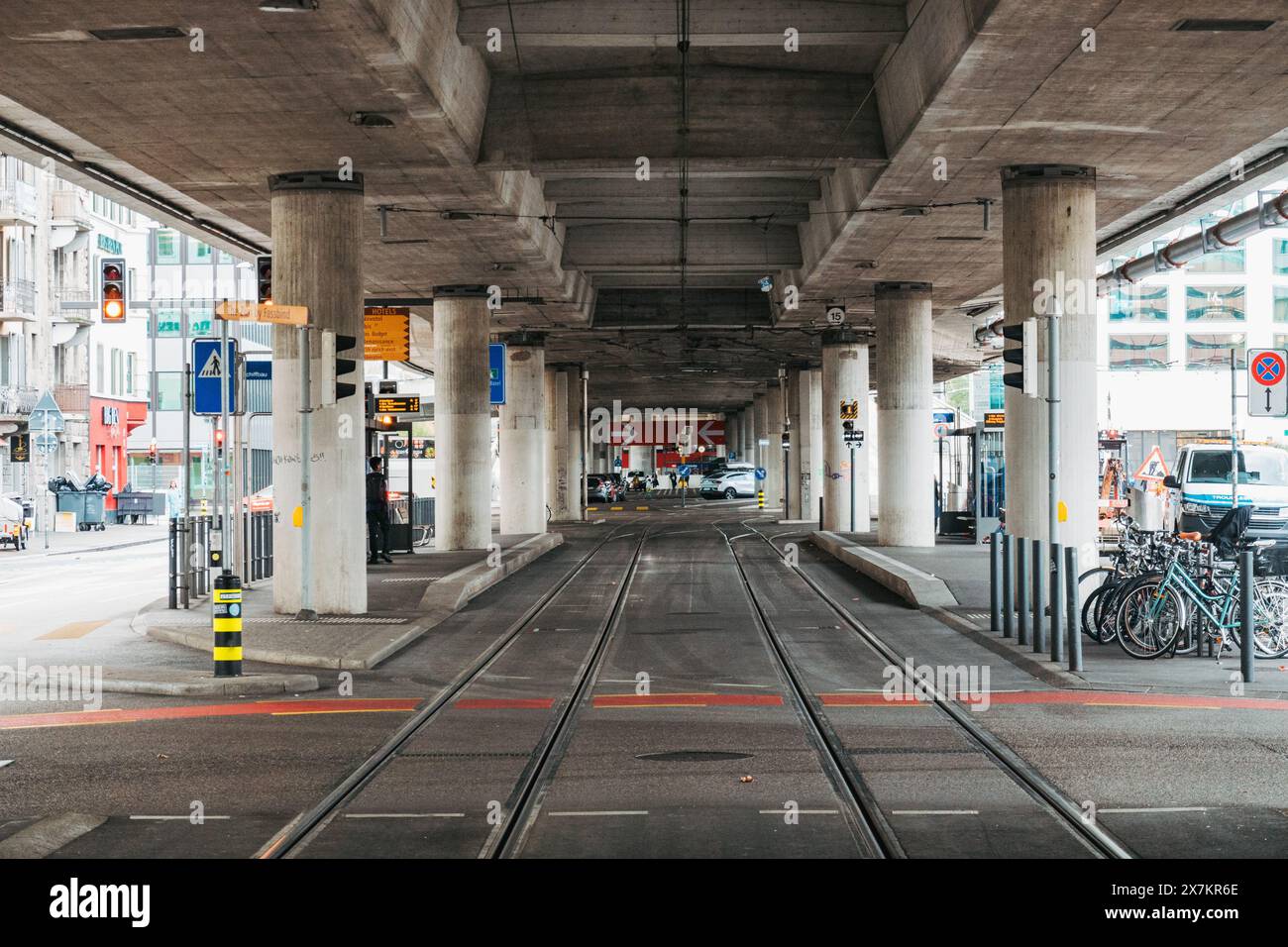 Guardando lungo i binari della metropolitana leggera alla stazione Schiffbau di Zurigo. Una strada a più corsie corre in alto, sostenuta da montanti in cemento Foto Stock