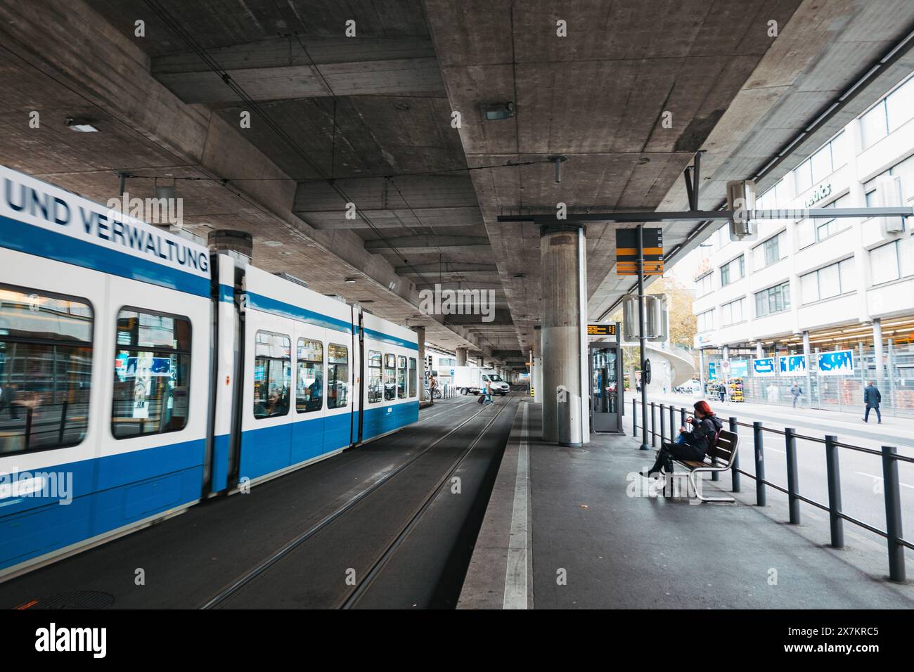 Un tram arriva alla stazione della metropolitana leggera di Schiffbau, Zurigo, sotto una strada a più corsie sopraelevata da pilastri di cemento Foto Stock