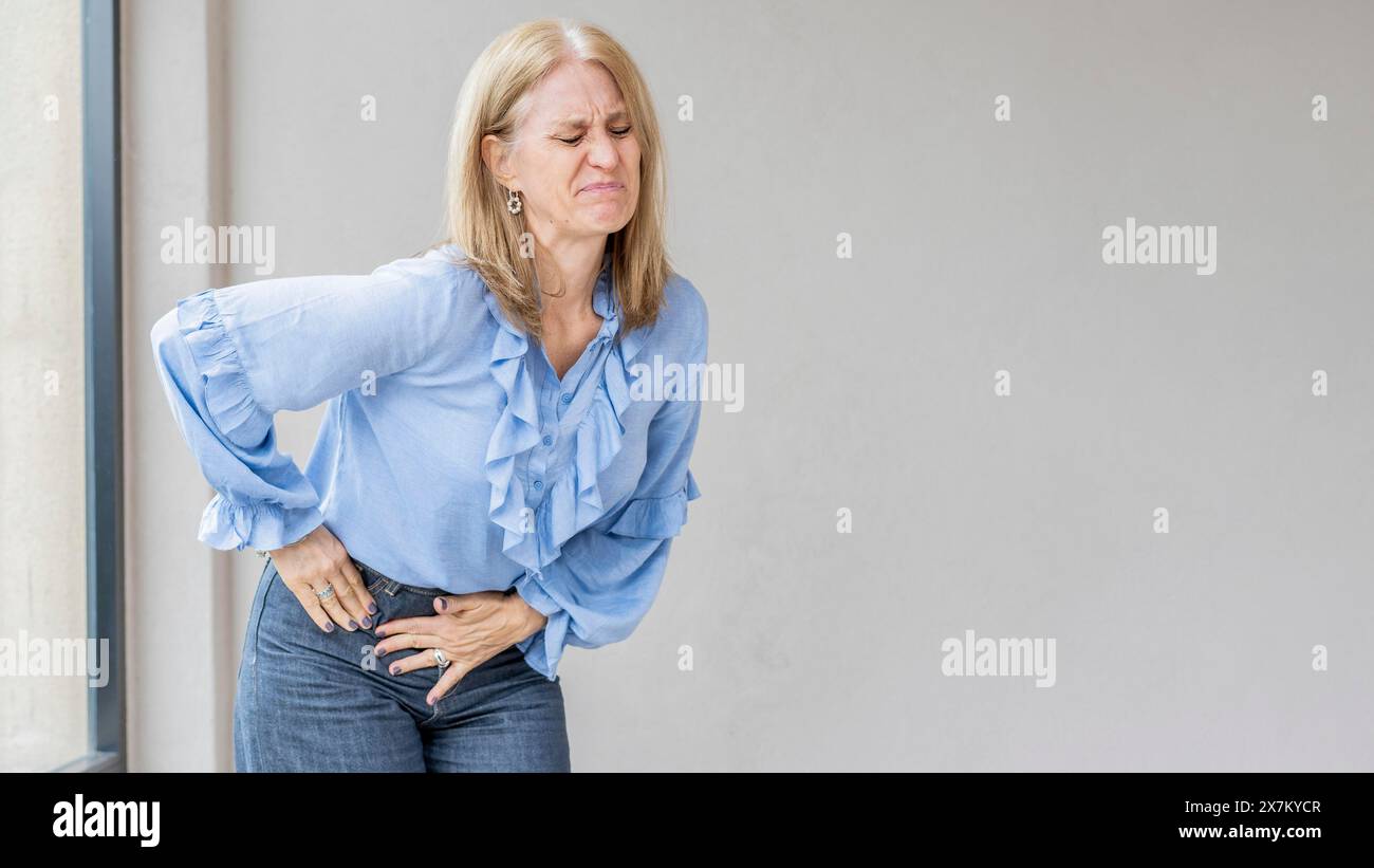 Una donna bionda sta soffrendo perché soffre di dolore per l'appendice Foto Stock