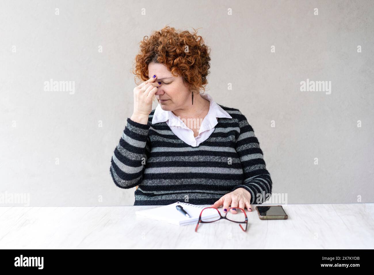 Una donna rossa di mezza età ha smesso di lavorare a causa di un mal di testa Foto Stock