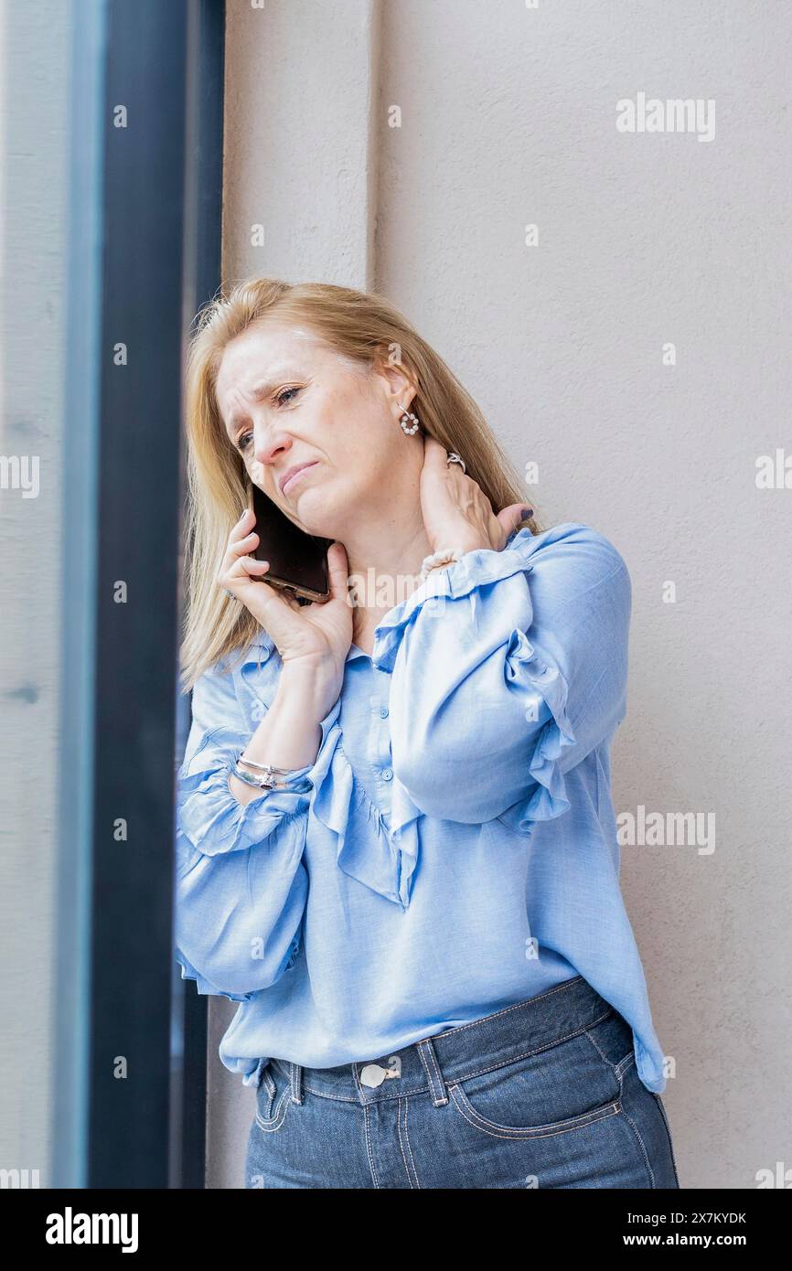 Donna stanca che parla al telefono con dolore al collo Foto Stock