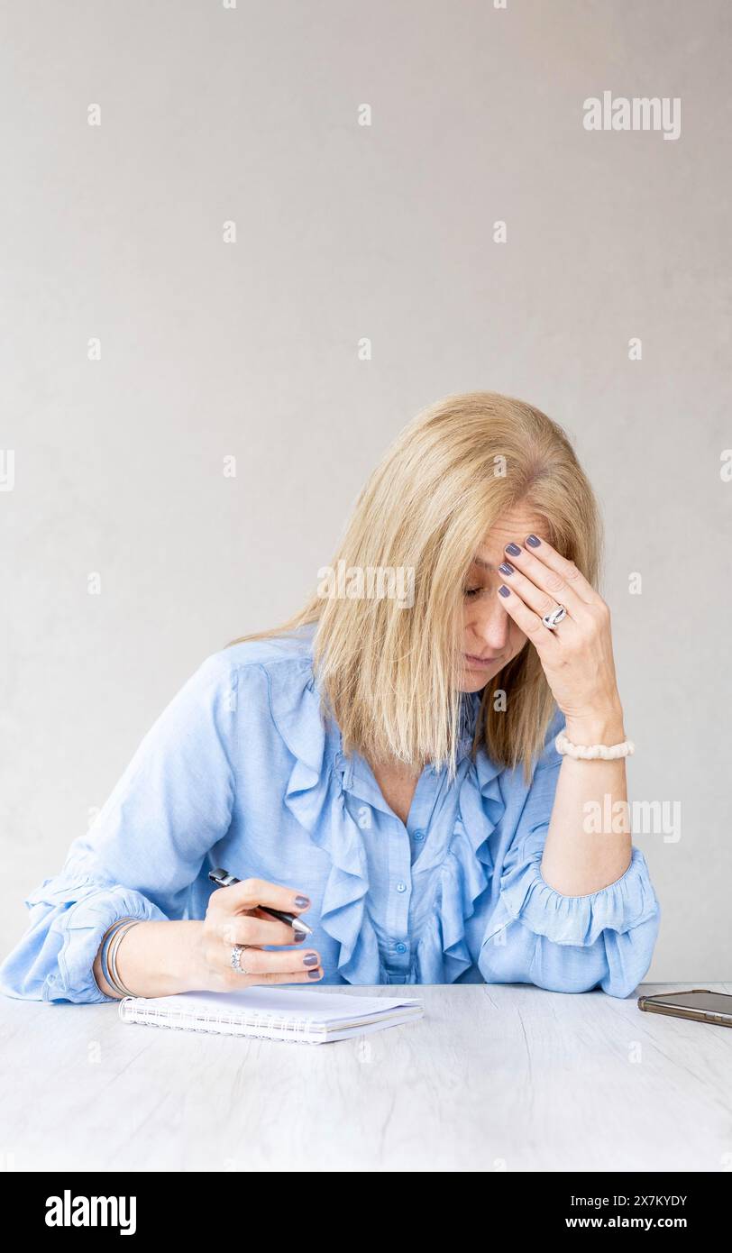 Donna stanca che tocca la fronte con mal di testa emicrania. Scatto verticale Foto Stock