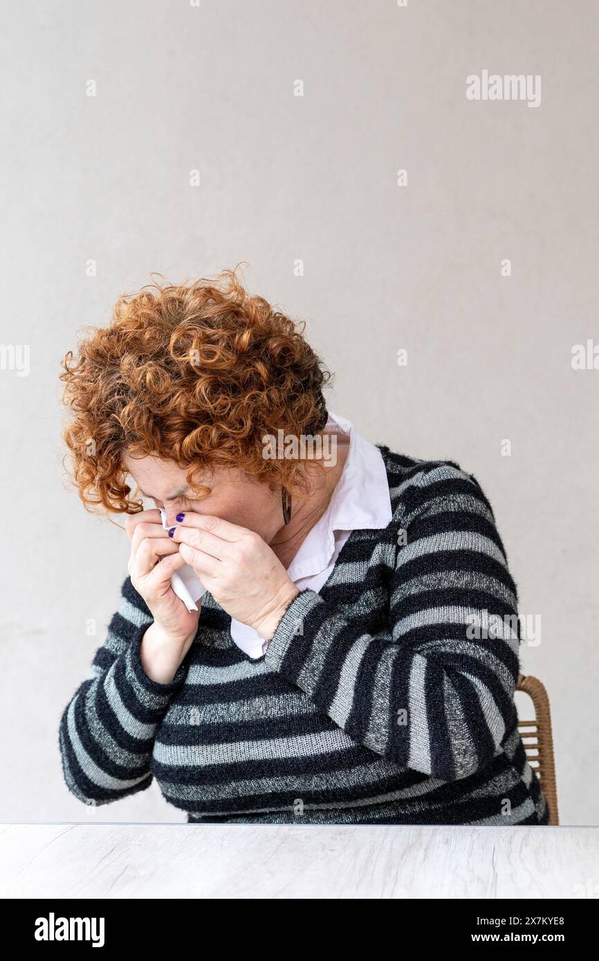 Vista laterale di una donna che soffia il naso Foto Stock