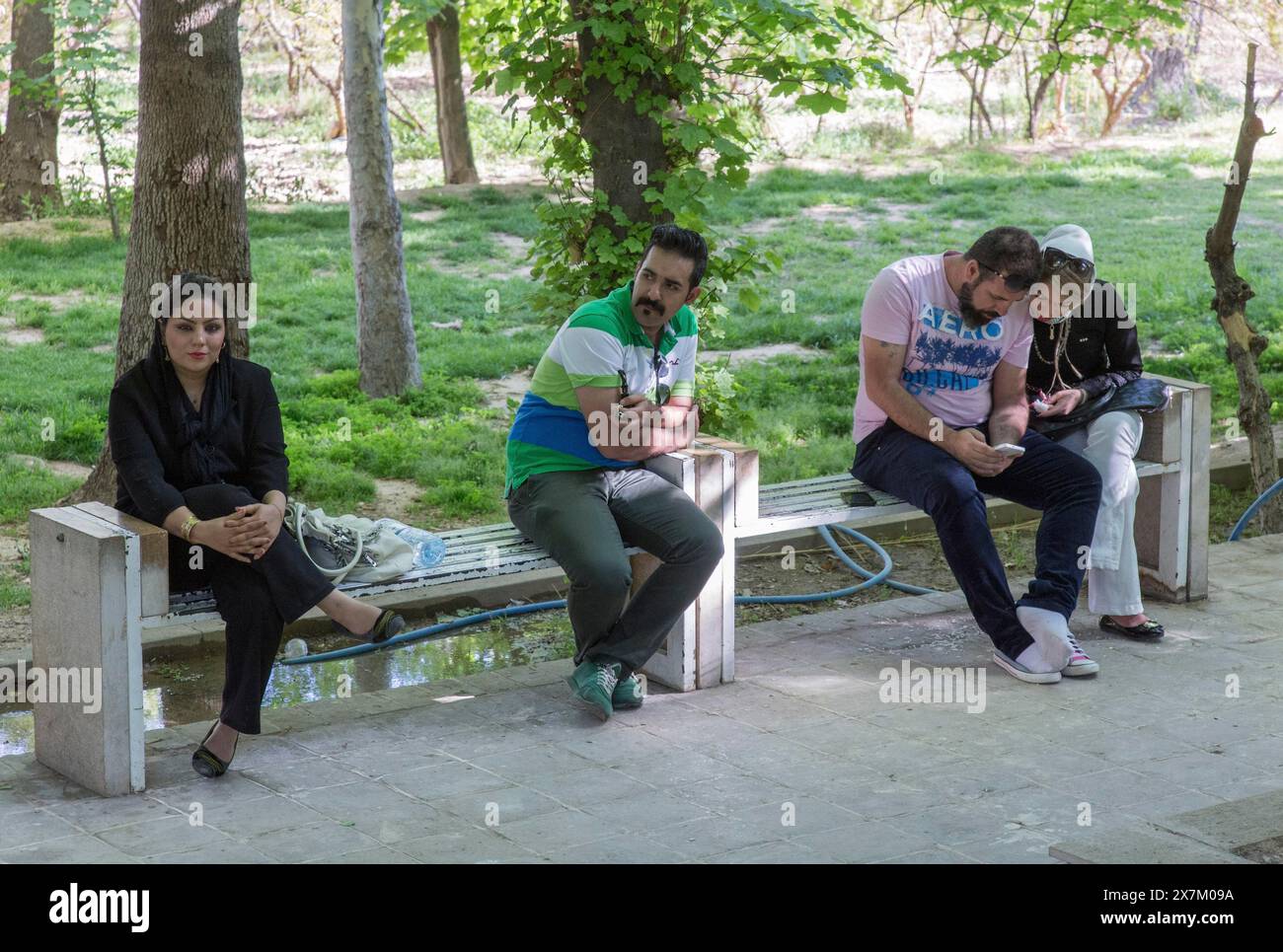 Una giovane coppia iraniana una donna iraniana e un uomo iraniano il 03/04/2015 seduta su una panchina nel giardino tropicale di Shiraz, Shiraz, Iran Foto Stock