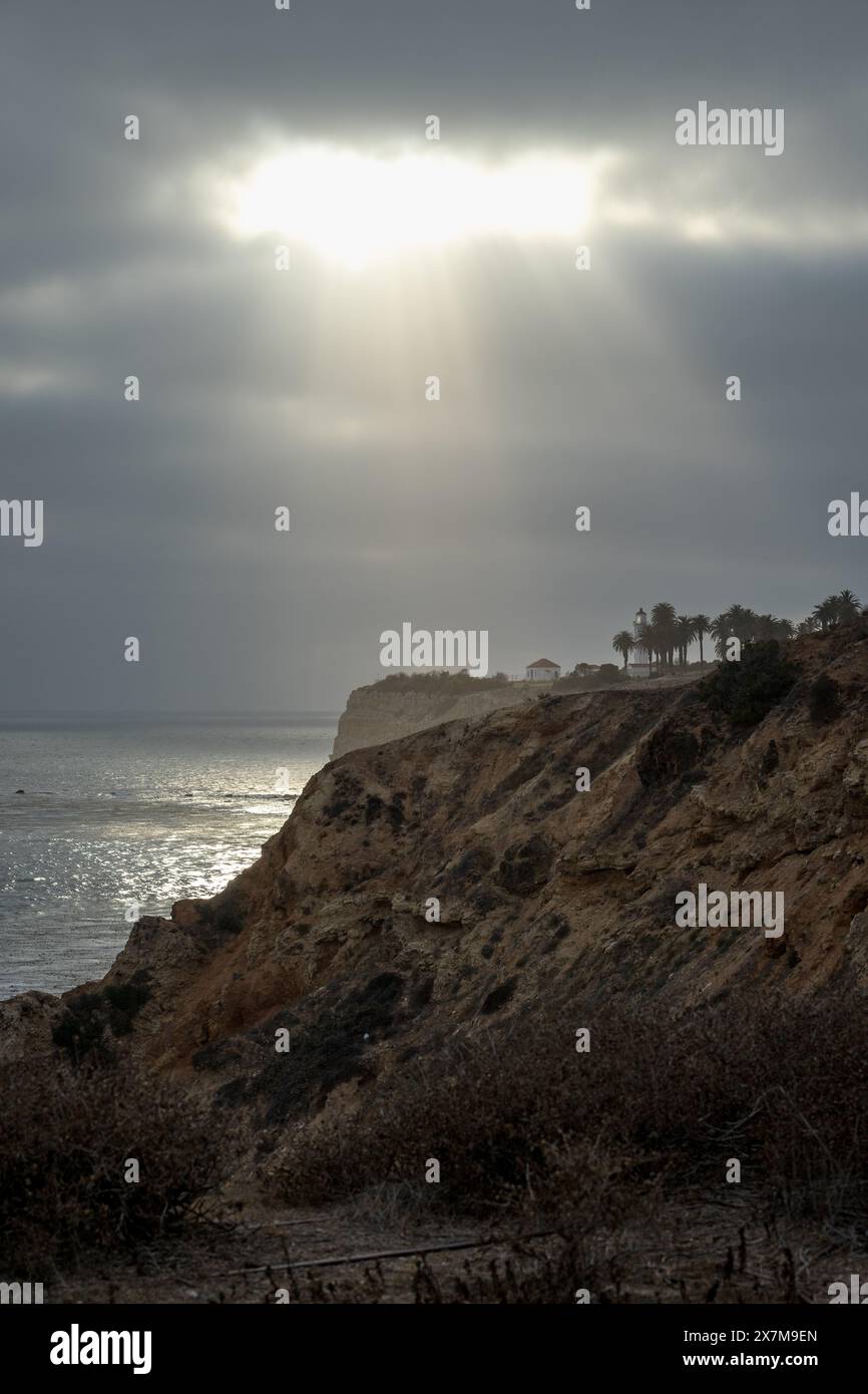 Le aspre scogliere di Point Vicente sono adornate da fasci di luce che penetrano attraverso il cielo coperto, evidenziando la serena bellezza di Rancho Palos V. Foto Stock