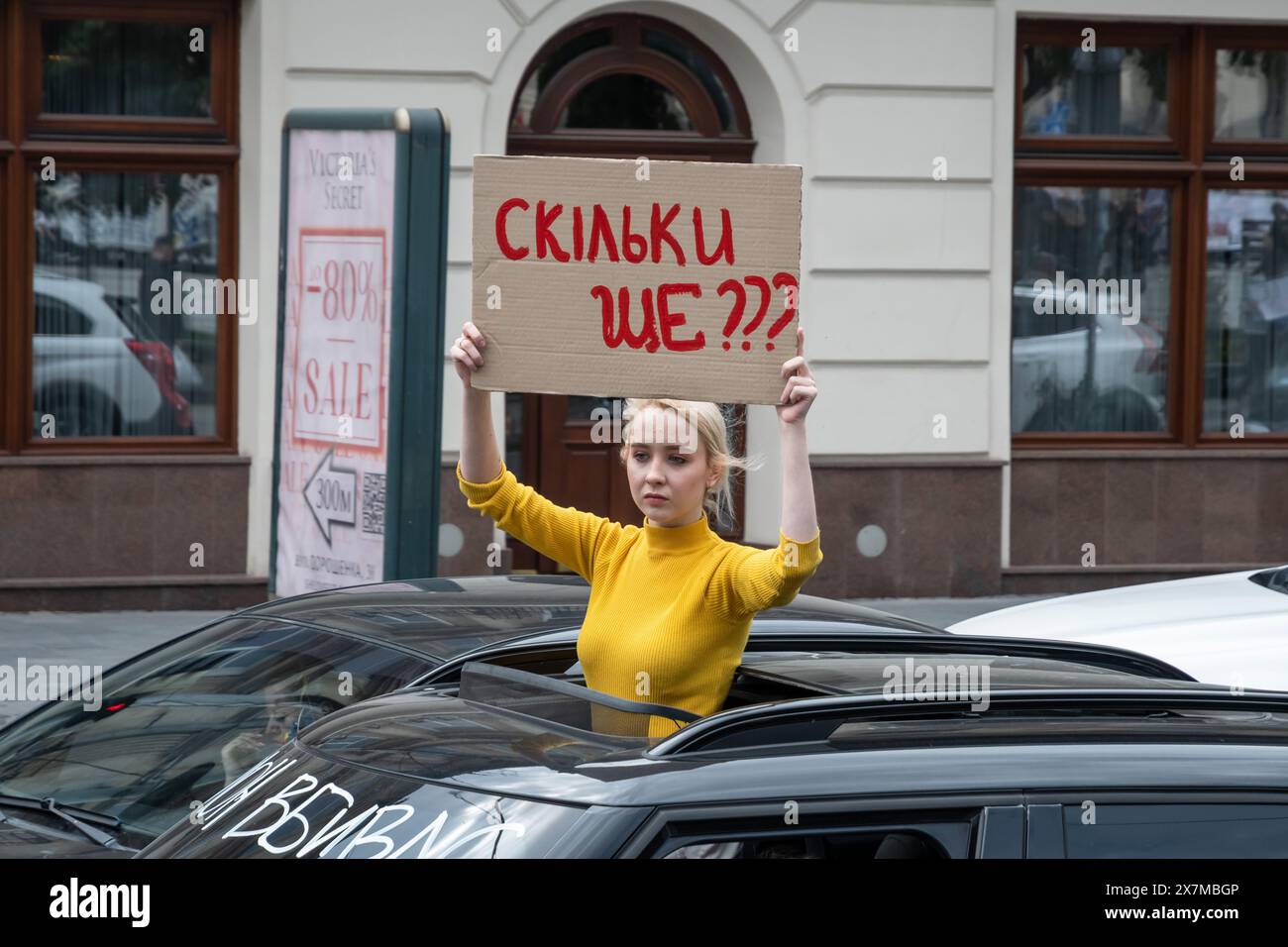 Una donna con uno striscione guida un'auto nel centro di Leopoli, Ucraina e protesta parenti e amici dei difensori catturati di Mariupol, tenendo striscioni e bandiere partecipano alla riunione del 'non tacere. Cattura uccide. Due anni di prigionia' dedicati all'anniversario della liberazione dei difensori ucraini dallo stabilimento Azovstal, a Leopoli. L'evento è organizzato dall'Associazione delle famiglie dei difensori di Azovstal. Il 20 maggio 2022, i difensori di Azovstal lasciarono l'impianto e furono catturati dai russi. Più di 2.000 soldati ucraini sono ancora in prigionia in terribili condi Foto Stock