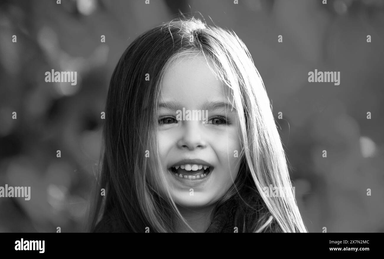 Primo piano ritratto di adorabile ragazza felice bambino su foglie caduto in su, giocando nel parco autunnale all'aperto. Foto Stock