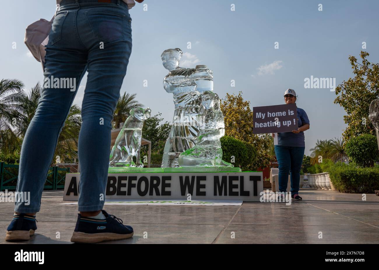 Un attivista di Greenpeace tiene un cartello di protesta accanto a una scultura di ghiaccio che si sta sciogliendo sotto l'ondata di caldo a Delhi, per mostrare l'impatto delle ondate di calore in tutto il paese, come parte di una protesta organizzata da un attivista di Greenpeace al Select City Mall di Saket. La scultura di ghiaccio alta 8 metri, che mostra una donna con un bambino e un cane, rappresenta alcune delle comunità più vulnerabili colpite dalle ondate di calore e da altri eventi meteorologici estremi. Mentre si scioglie nel sole di Delhi, invia un messaggio "agisci prima di scioglierci”, esortando l'Autorità nazionale per la gestione delle catastrofi a dichiarare le ondate di calore un disastro nazionale. Foto Stock