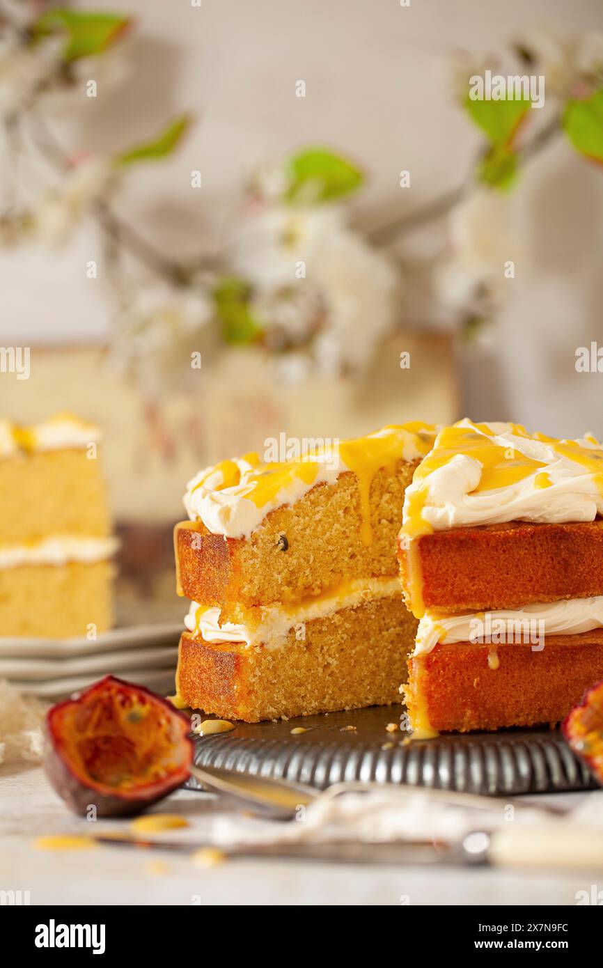 Una torta di spugne al frutto della passione con una fetta rimossa. Farcito con crema di mascarpone, cagliata di frutta passionata e coulis di frutta passionata. Foto Stock