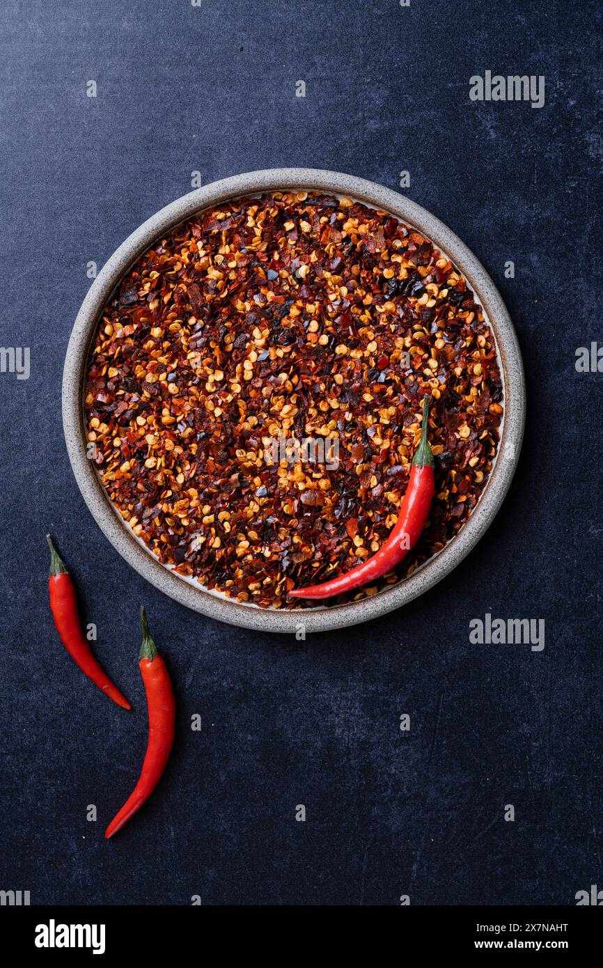 Peperoncini su un piatto con peperoncini crudi su sfondo blu Foto Stock