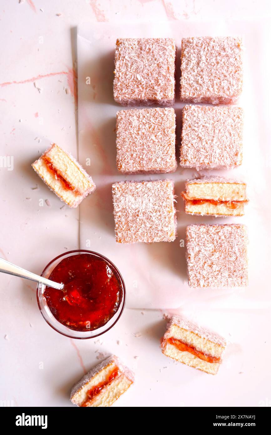 Torte quadrate di Lamington rosa australiana con confettura di fragole e ricoperte di cocco. Foto Stock