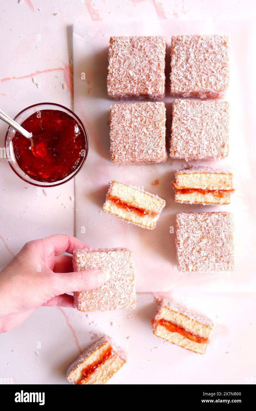 Torte quadrate di Lamington rosa australiana con confettura di fragole e ricoperte di cocco. Foto Stock