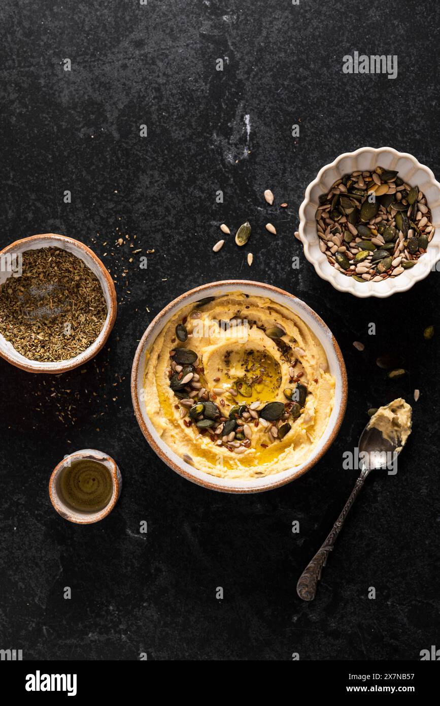 Ciotola di hummus con semi, olio d'oliva, origano Foto Stock