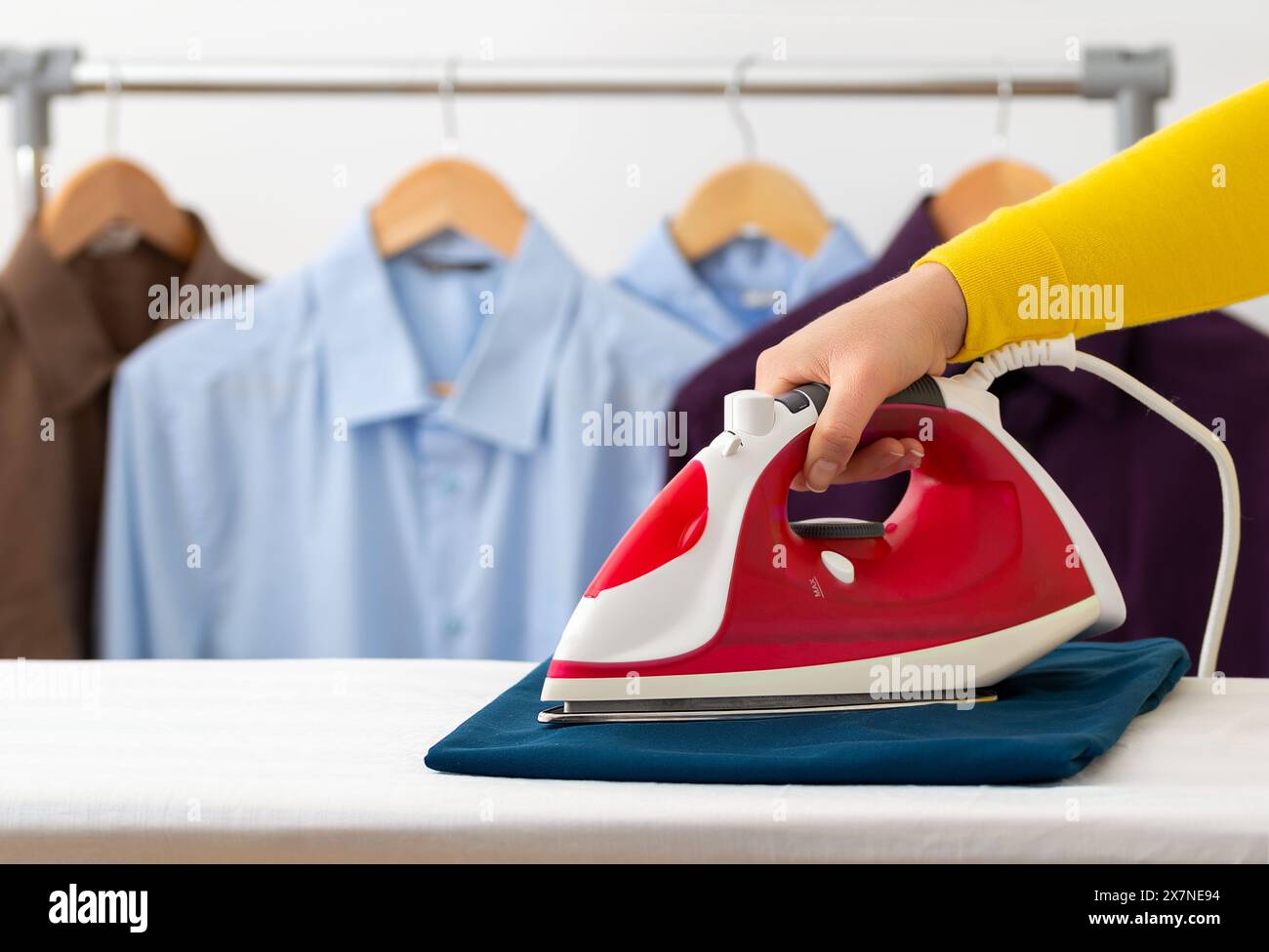 Primo piano di una donna non identificabile che stira vestiti a casa con spazio copia. Foto Stock