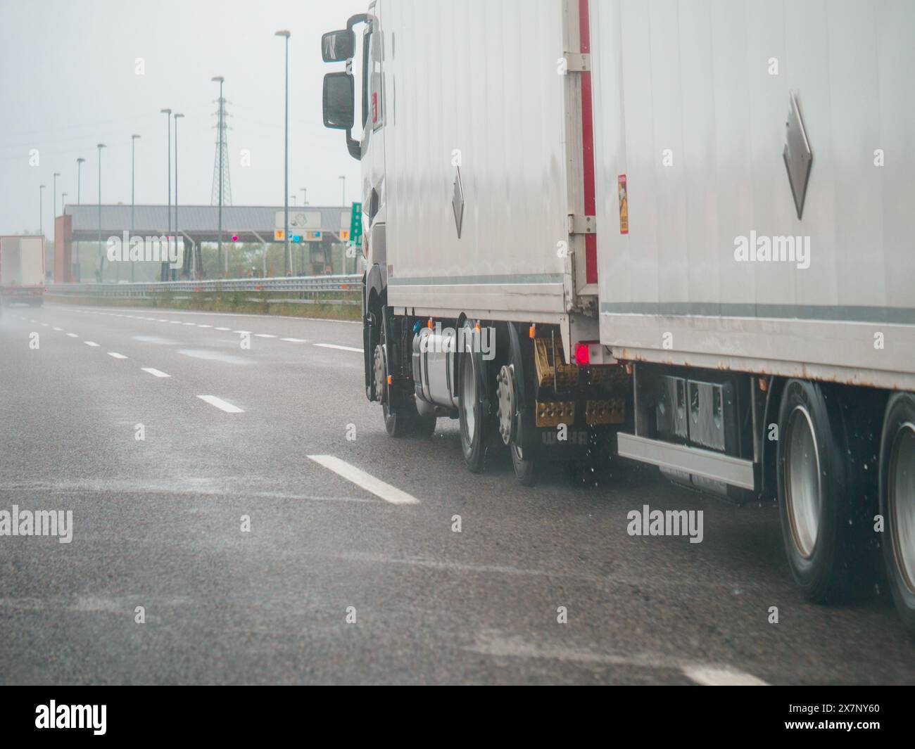 Piacenza, Italia - 22 aprile 2024 Una scena autostradale sotto un cielo coperto con auto e camion con segnaletica stradale e un cavalcavia, giornata di pioggia su Motorwa Foto Stock