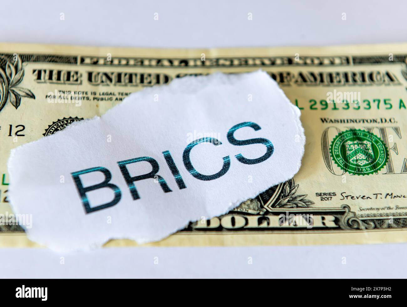 Un concetto di dedollarizzazione con la parola BRICS in cima a un conto in dollari USA isolato in bianco. Foto Stock