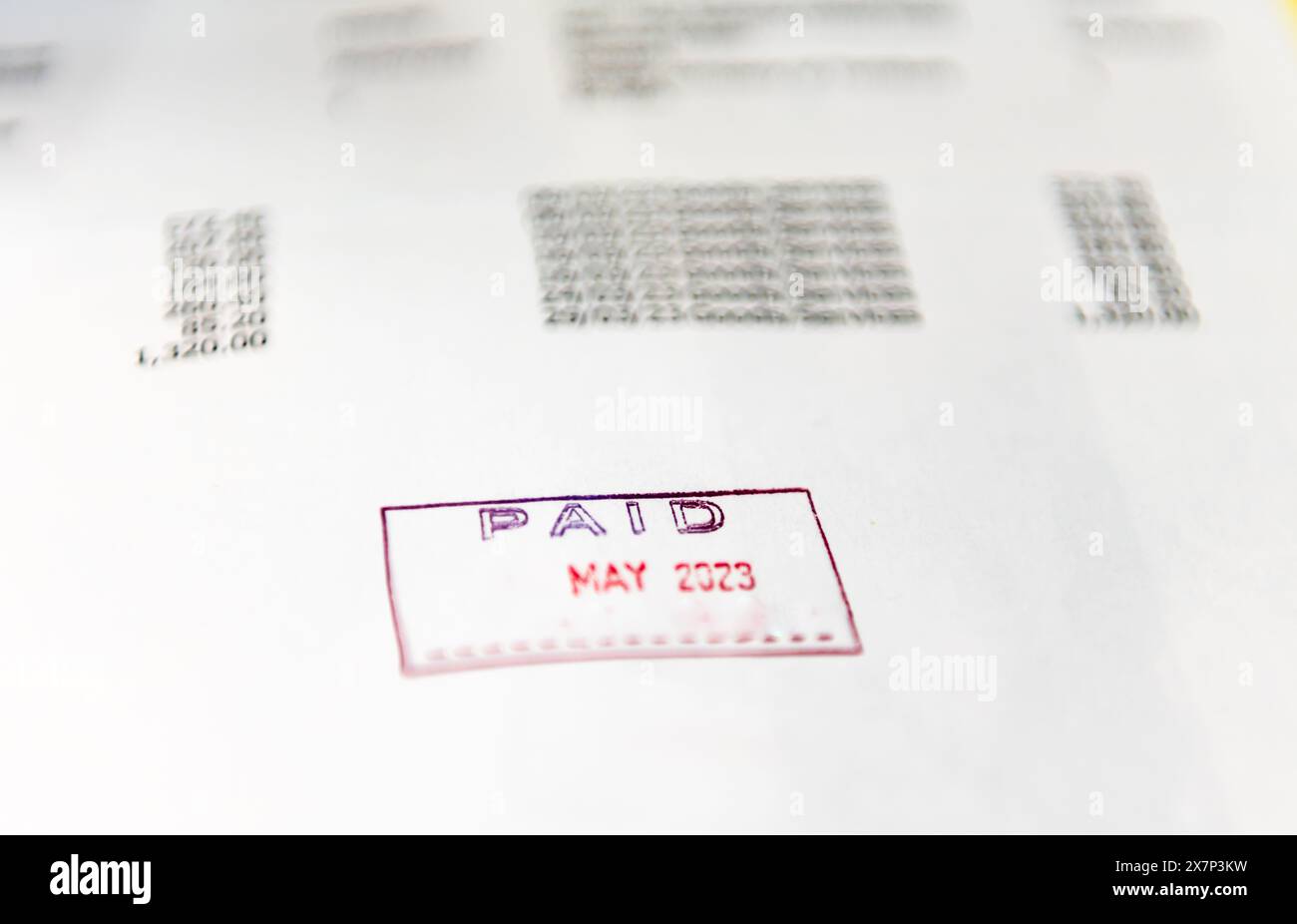 Un concetto di contabilità con primo piano di una fattura aziendale timbrata con la parola pagato. Foto Stock