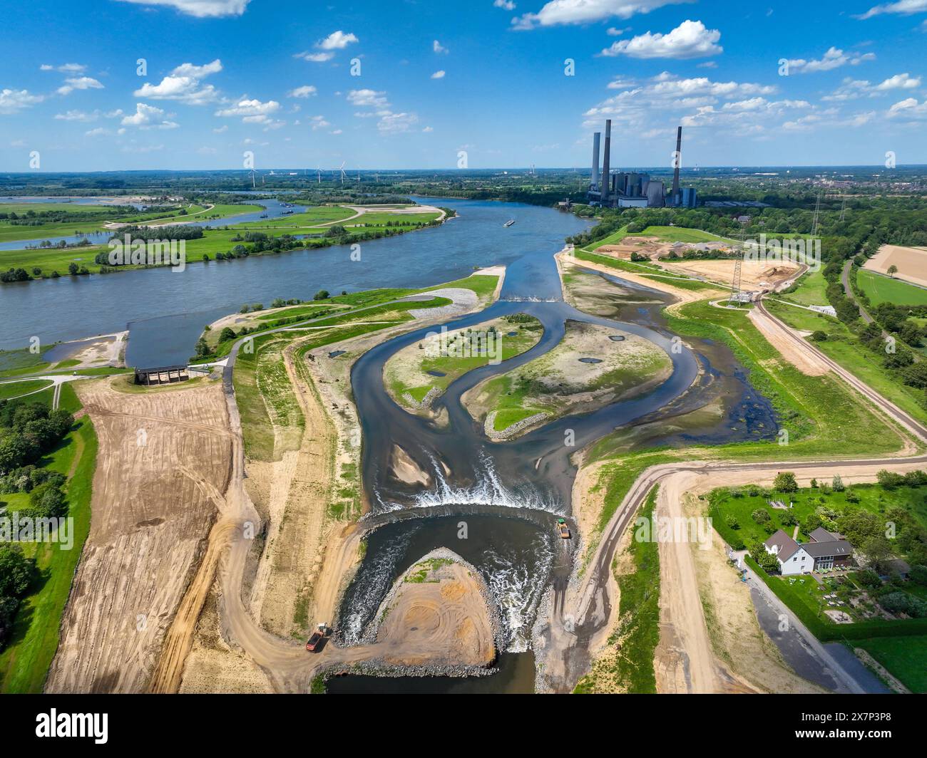 Dinslaken, Voerde, Nordrhein-Westfalen, Deutschland - Renaturierung der Emscher. Neue Emschermuendung nel Reno. Hochwasserschutz durch Flaechenausweitung. Hinten das stillgelegte STEAG Steinkohlekraftwerk Voerde. Die Muendung der Emscher in den Rhein wurde von Dinslaken um knapp 500 Meter noerdlich nach Voerde verlegt. Fische koennen jetzt vom Rhein durch ein neu geschaffenes Auengebiet barrierefrei die neue Emscher hochschwimmen. Die Emscher ist nach dem Bau eines Parallel verlaufenden Abwasserkanals seit Januar 2022 komplett abwasserfrei. Der Fluss guerra vorher ein offener, oberirdischer M. Foto Stock