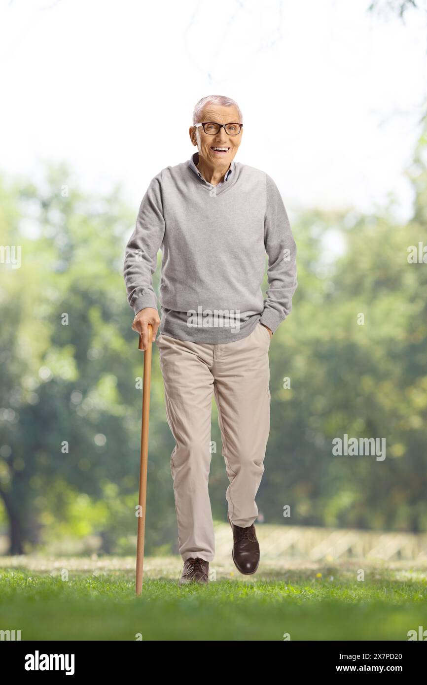 Uomo anziano con un bastone che cammina all'aperto in un parco Foto Stock