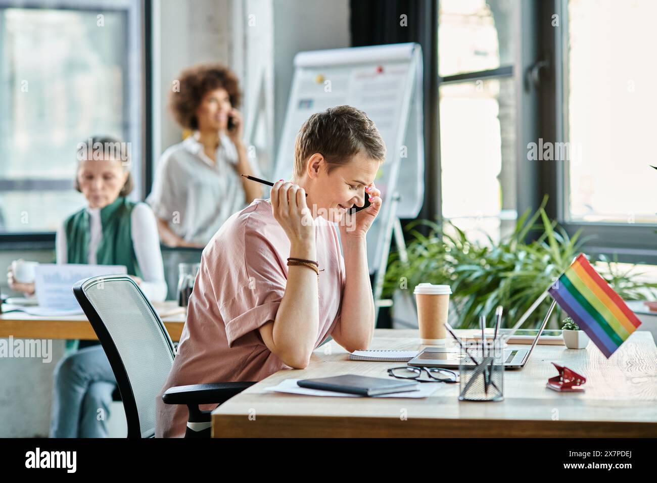Donna che lavora sodo e si occupa di lavoro, telefono, con i suoi colleghi diversi sullo sfondo. Foto Stock