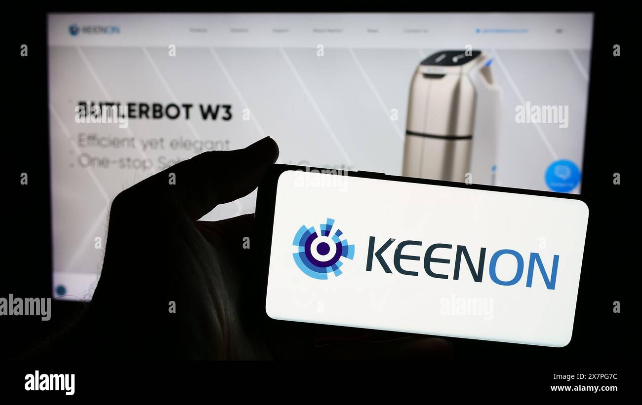 Persona che possiede uno smartphone con il logo della società cinese di robot di assistenza Keenon Robotics Co. Ltd. Davanti al sito Web. Mettere a fuoco il display del telefono. Foto Stock