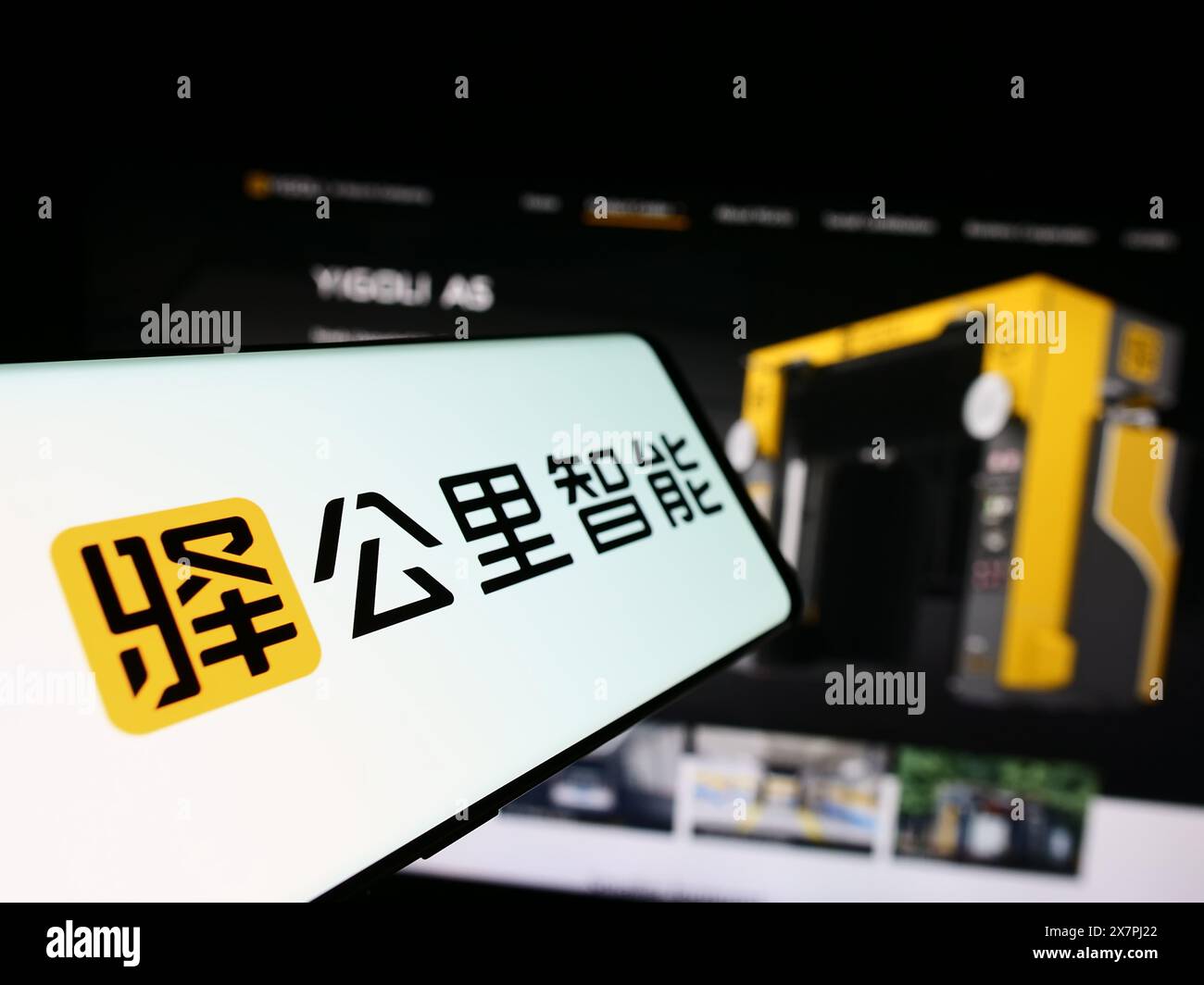 Telefono cellulare con logo della società tecnologica cinese Yigongli Intelligence (1KMXC) davanti al sito web. Mettere a fuoco la parte centrale sinistra del display del telefono. Foto Stock