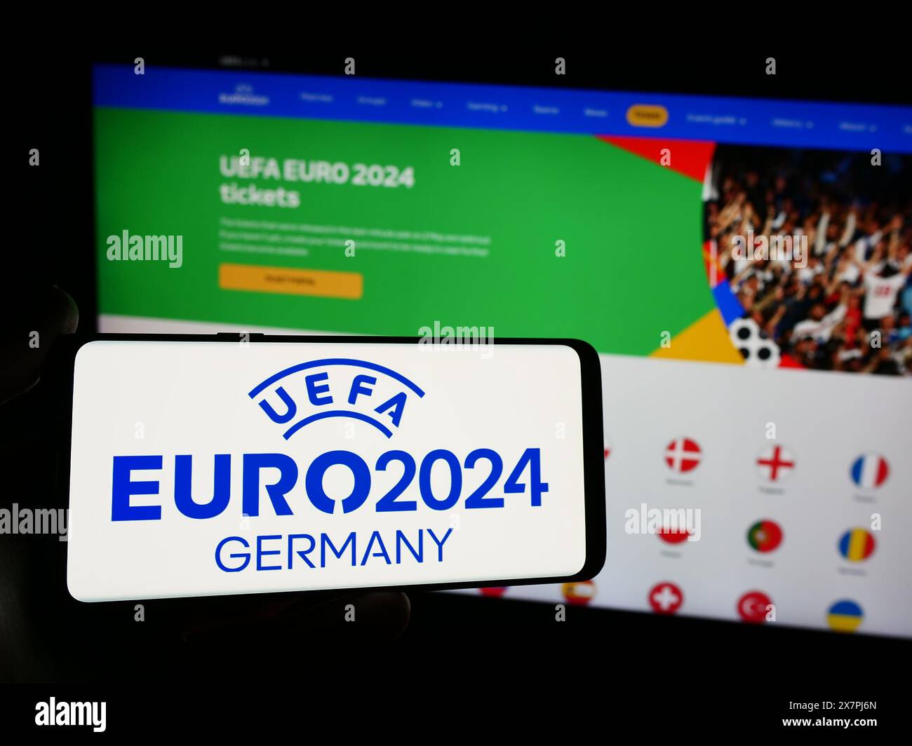 Persona con smartphone con logo del campionato europeo di calcio UEFA Euro 2024 davanti al sito web. Mettere a fuoco il display del telefono. Foto Stock