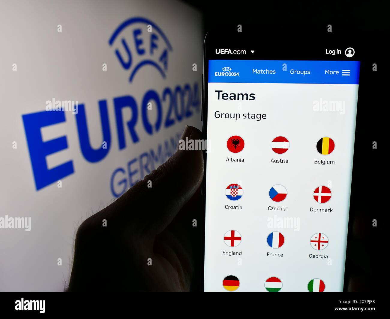 Persona con smartphone con pagina web del campionato europeo di calcio UEFA Euro 2024 davanti al logo. Messa a fuoco al centro del display del telefono. Foto Stock
