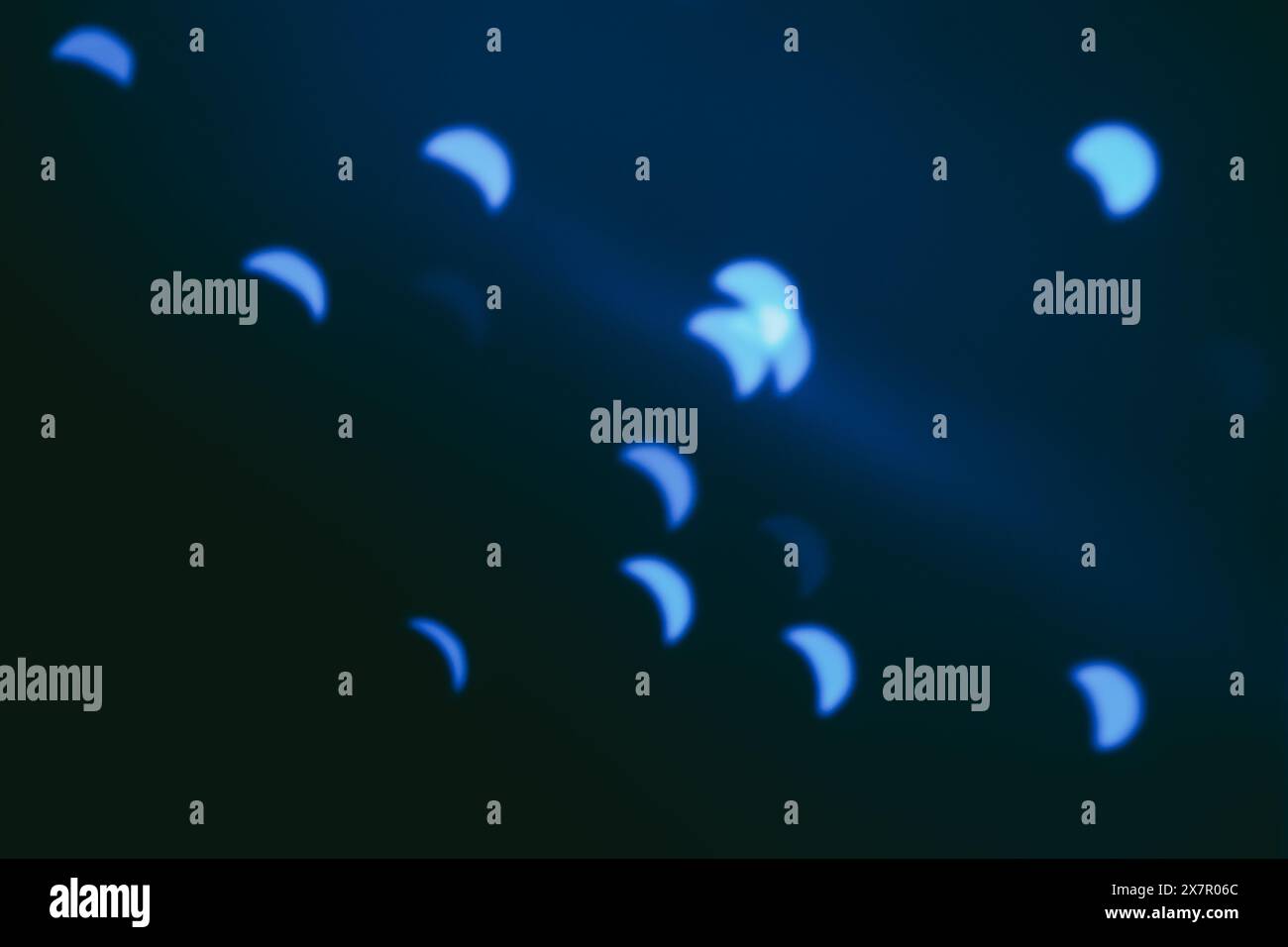 Questa immagine cattura una serie di forme blu astratte, che ricordano le lune a mezzaluna, sparse su uno sfondo scuro, creando un misterioso sogno Foto Stock