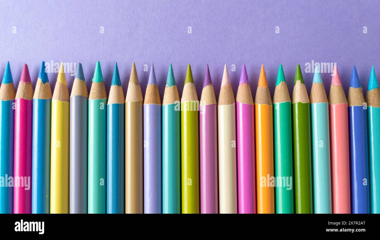 Pastelli di legno colorati su sfondo di carta viola Foto Stock