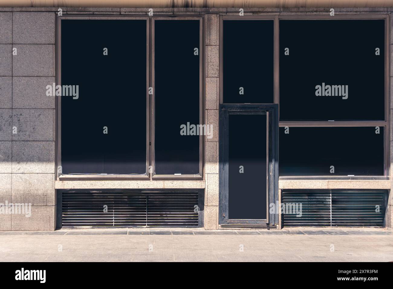 Un punto vendita vuoto a Madrid pronto per il branding e il design, caratterizzato da una facciata semplice con finestre e porte vuote Foto Stock