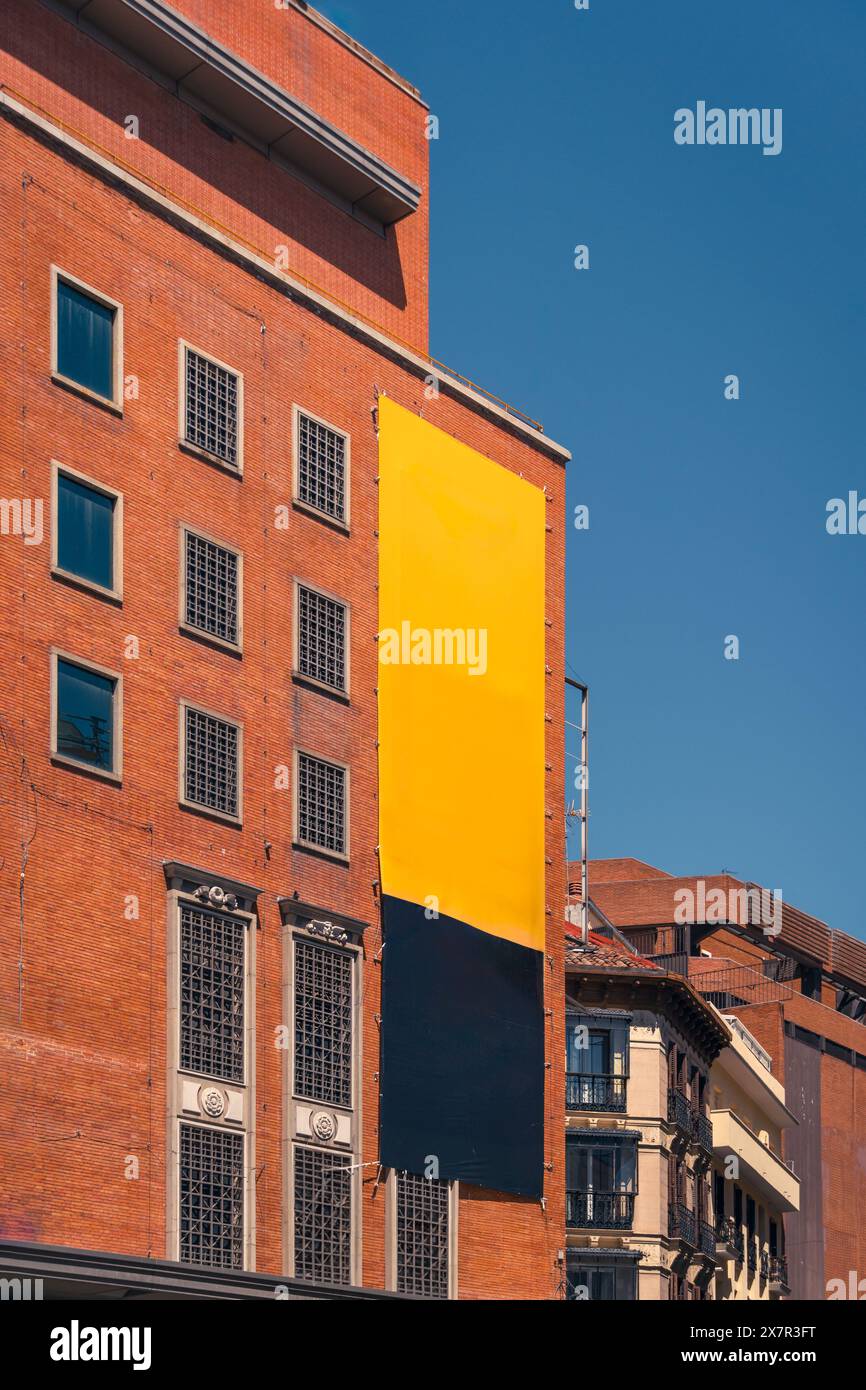 Grande insegna gialla e nera vuota su un edificio di mattoni rossi contro il cielo blu, perfetta per i mockup e gli annunci pubblicitari a Madrid Foto Stock