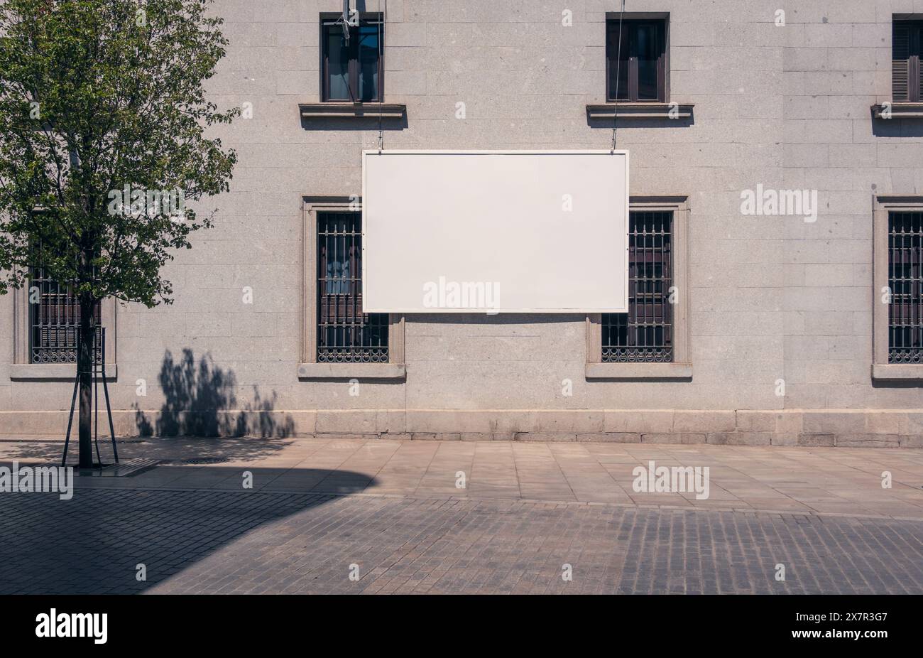 Un grande cartellone bianco è appeso alla parete esterna di un edificio a Madrid, perfetto per i mockup pubblicitari Foto Stock