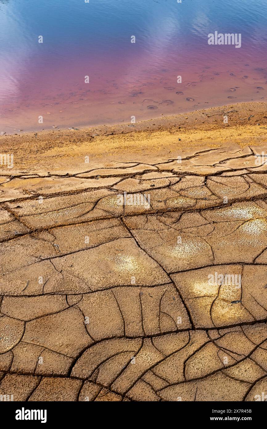 Immagine impressionante che mostra la terra incrinata e le ricche acque rosse del fiume riotinto, evidenziando i depositi minerali naturali e l'ambiente circostante Foto Stock